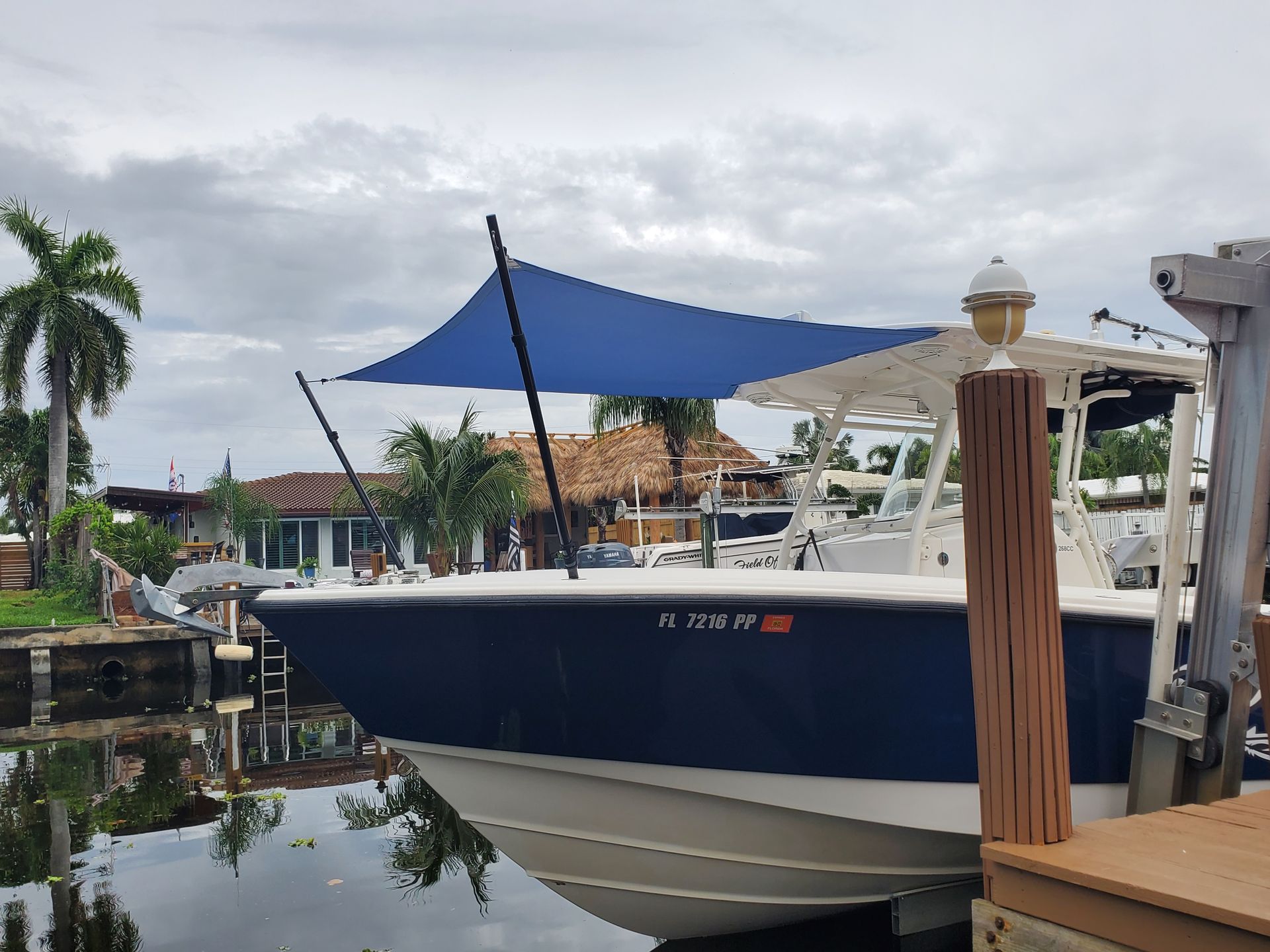 A boat is docked at a dock with a blue sail on top of it.
