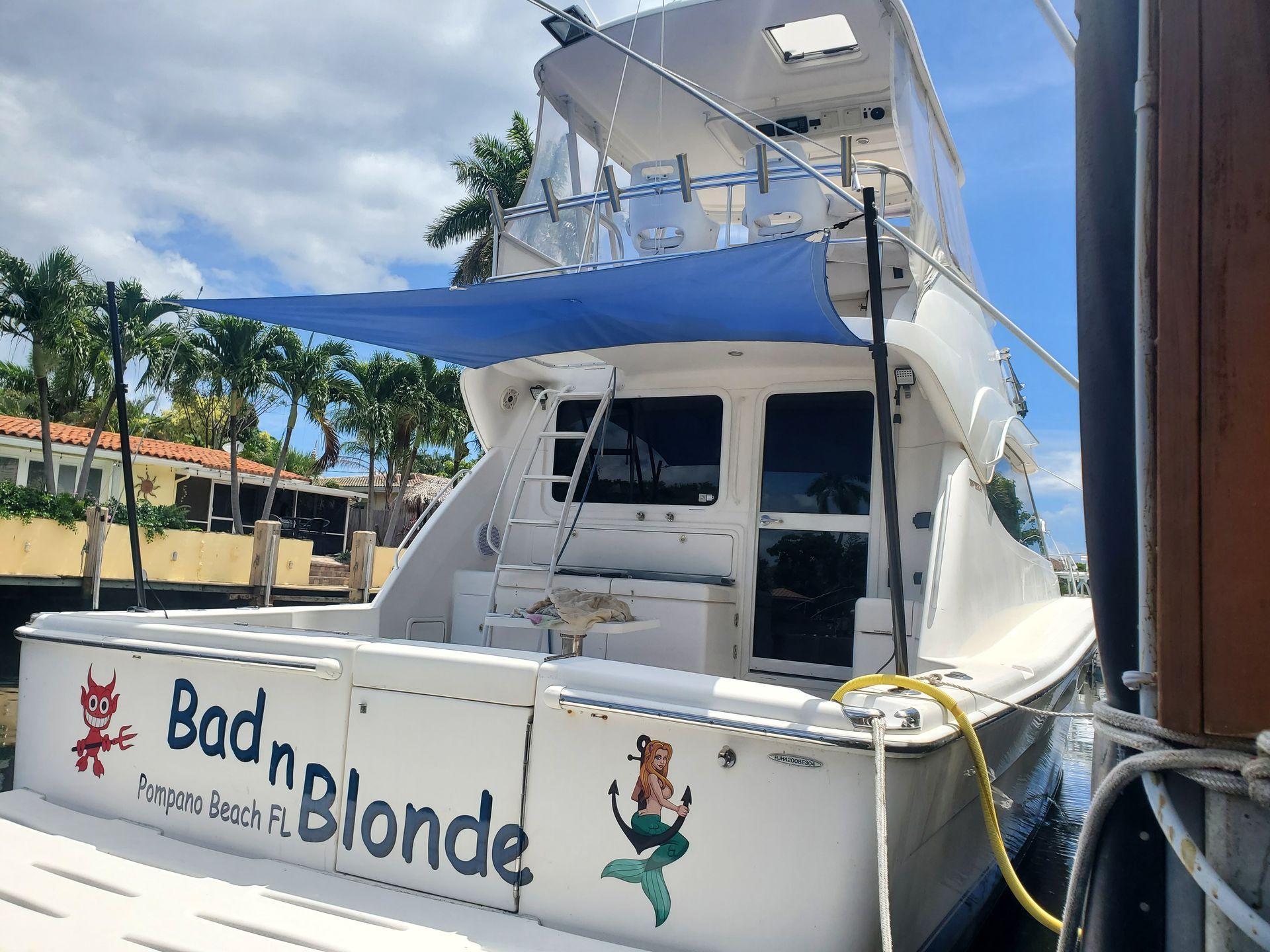 A white boat with the name bad n blonde on the side is docked at a dock.