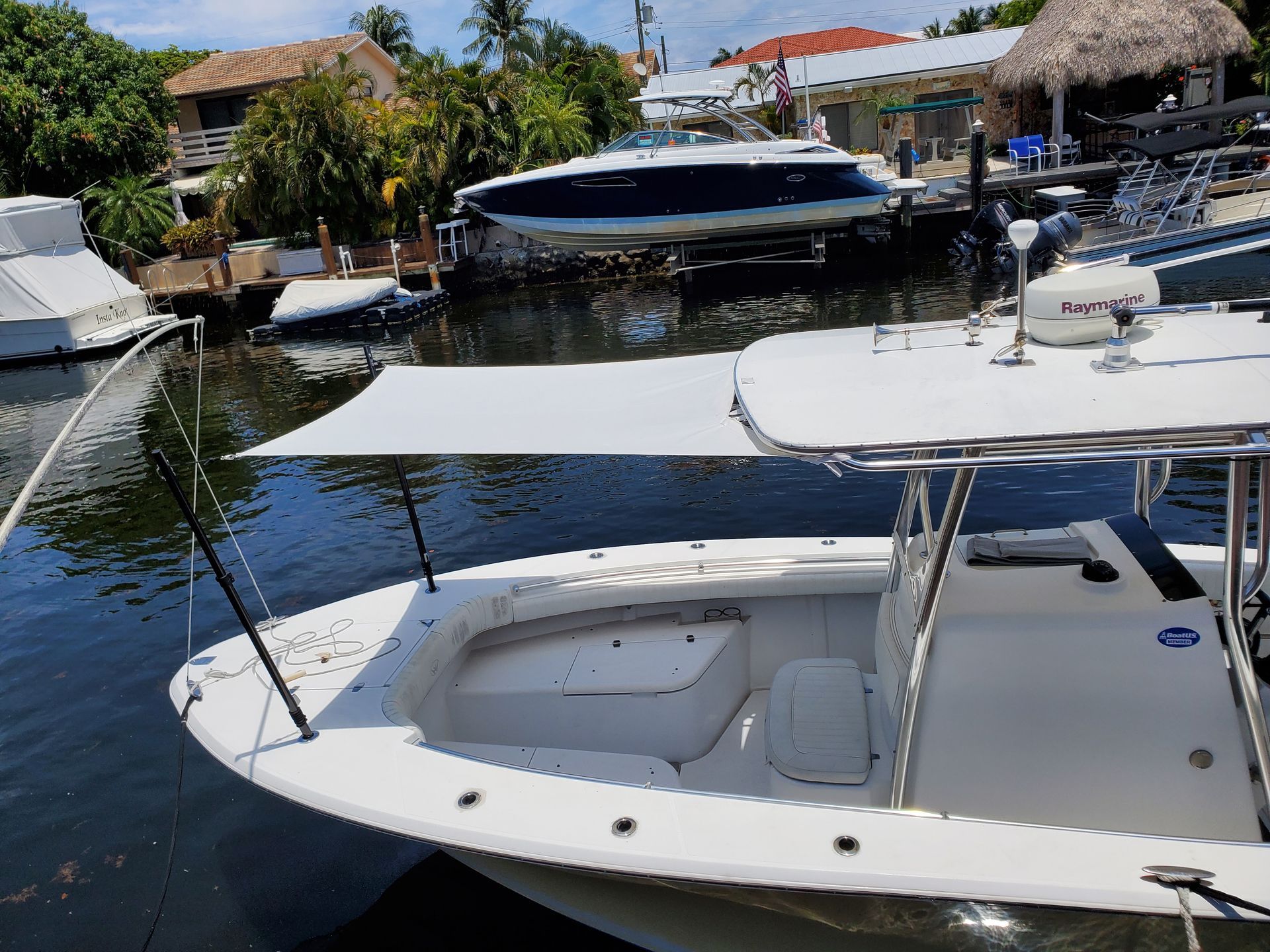 A white boat with a canopy is docked in a marina.