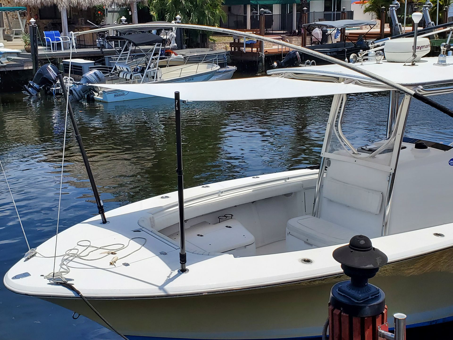 A white boat with a canopy is docked in the water
