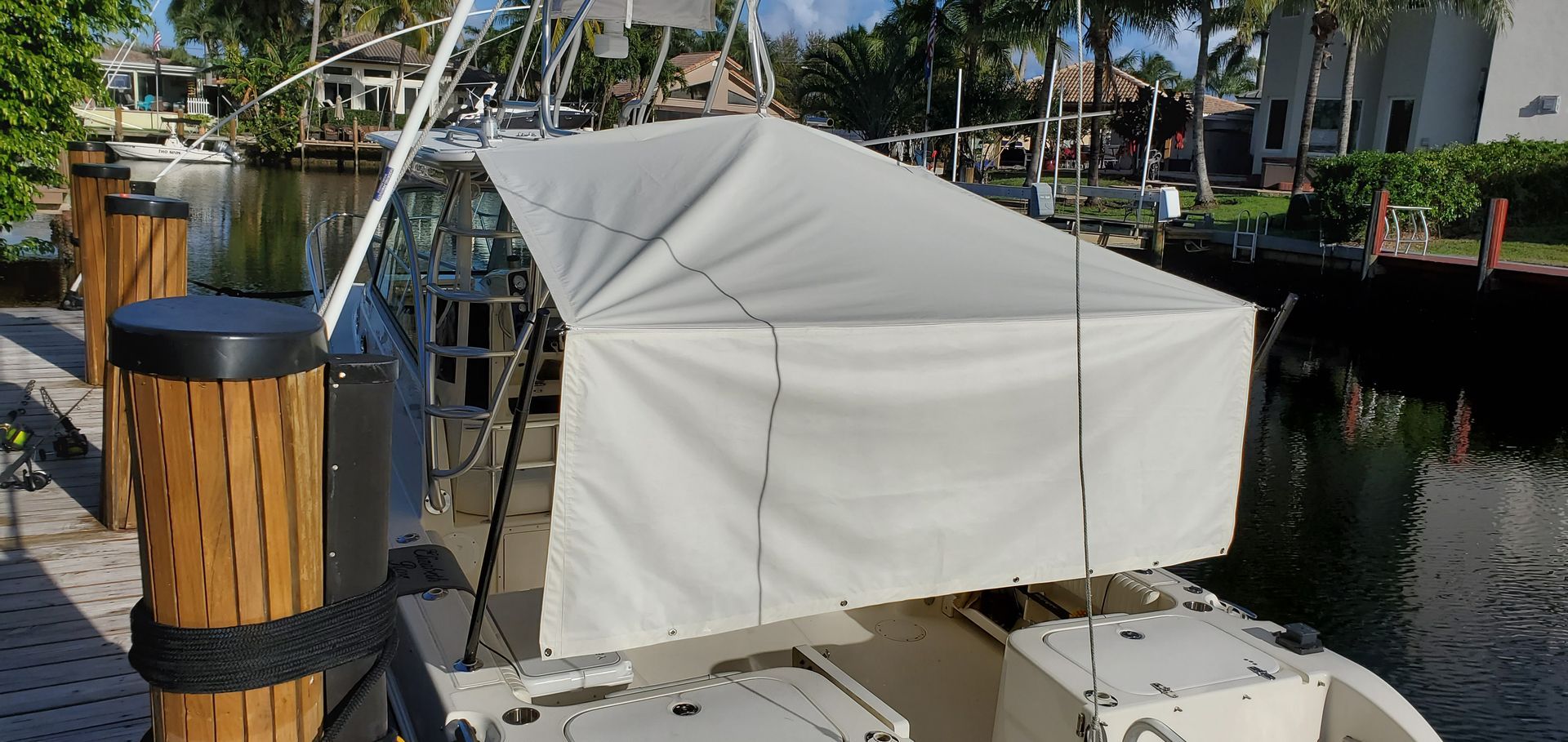 A boat with a white canopy is docked at a dock.