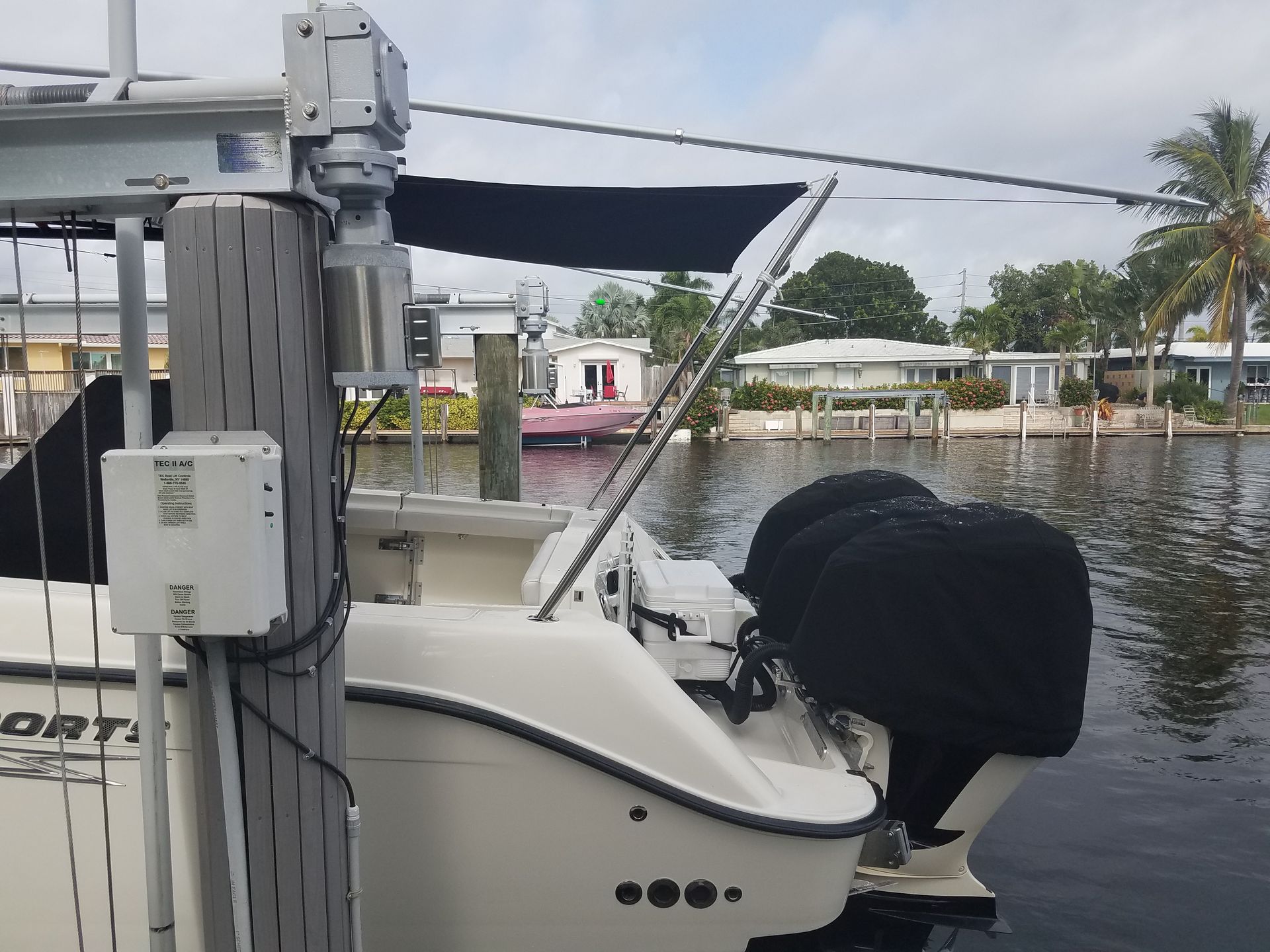 A white boat is docked at a dock with a black canopy