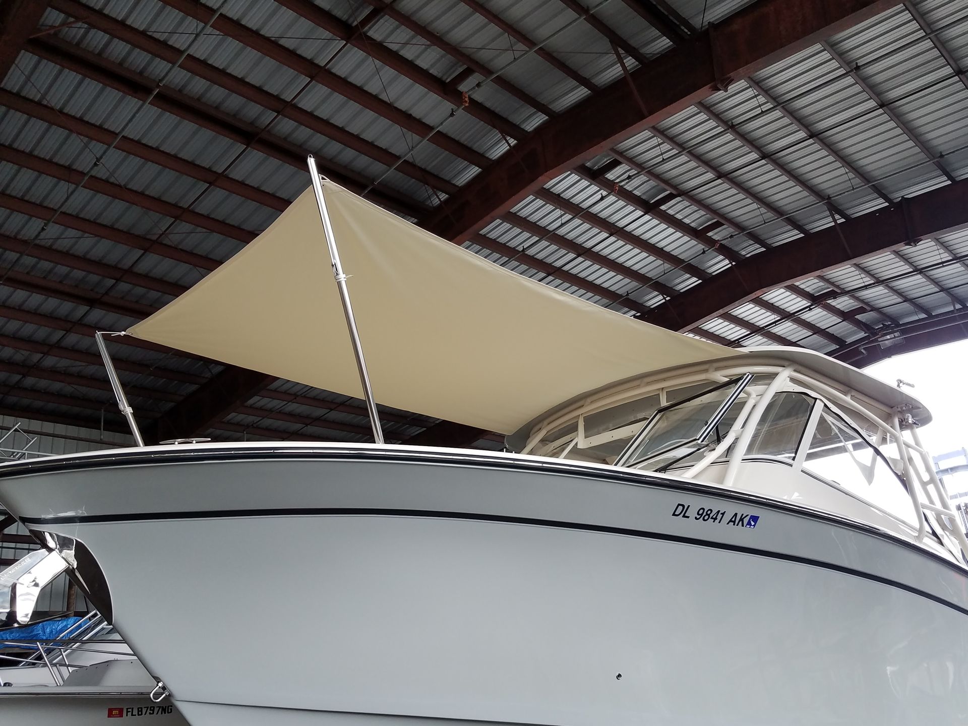 A boat is sitting under a roof with a sail on top of it.