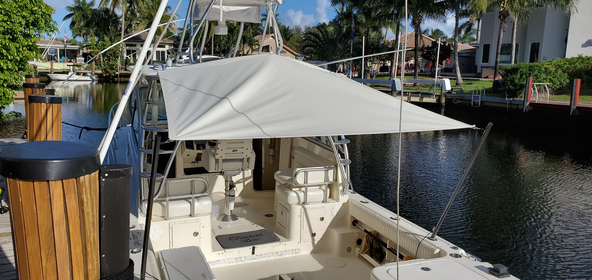 A boat with an umbrella on top of it is docked in a marina.
