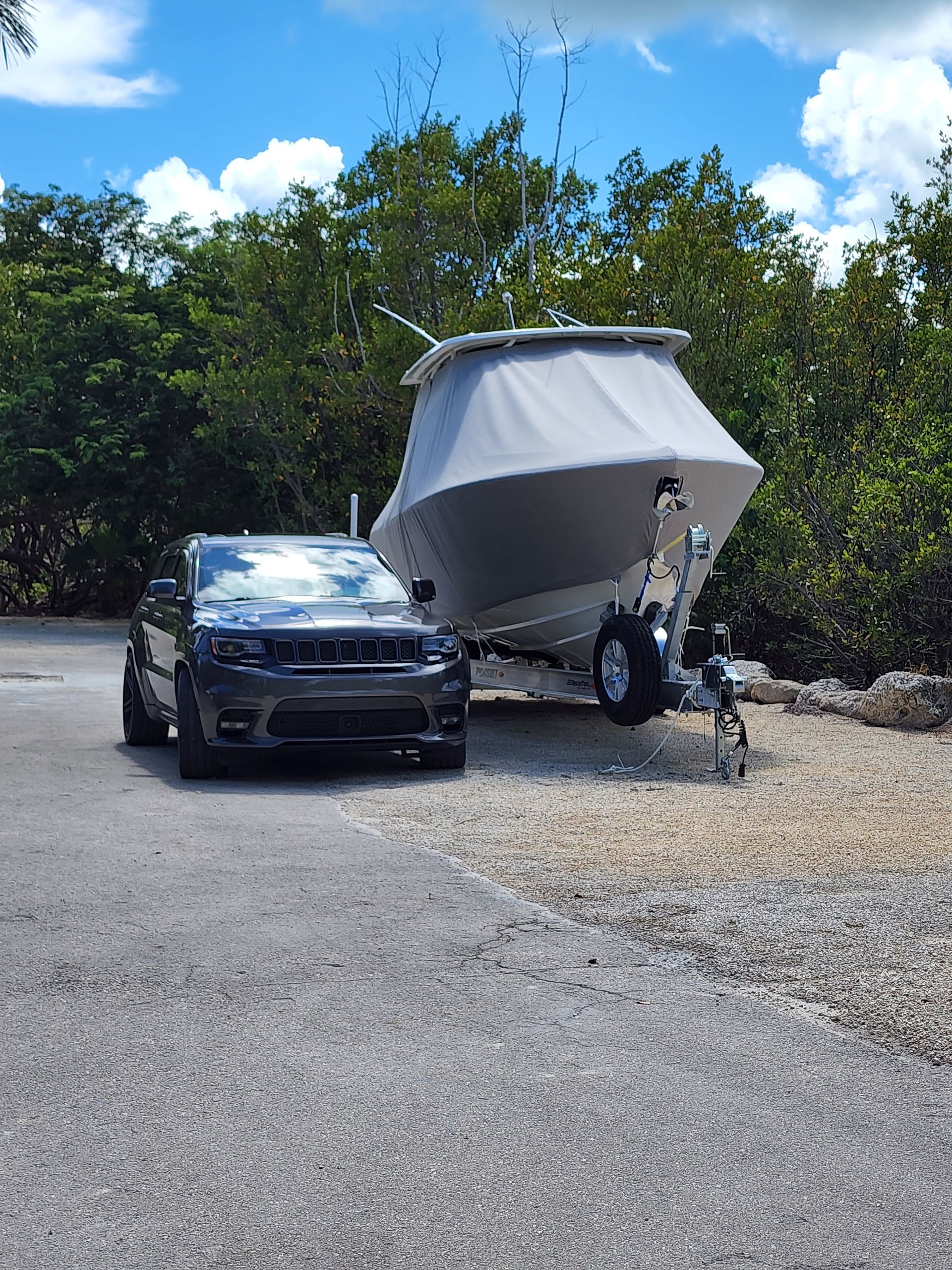 A car is parked next to a boat on a trailer.