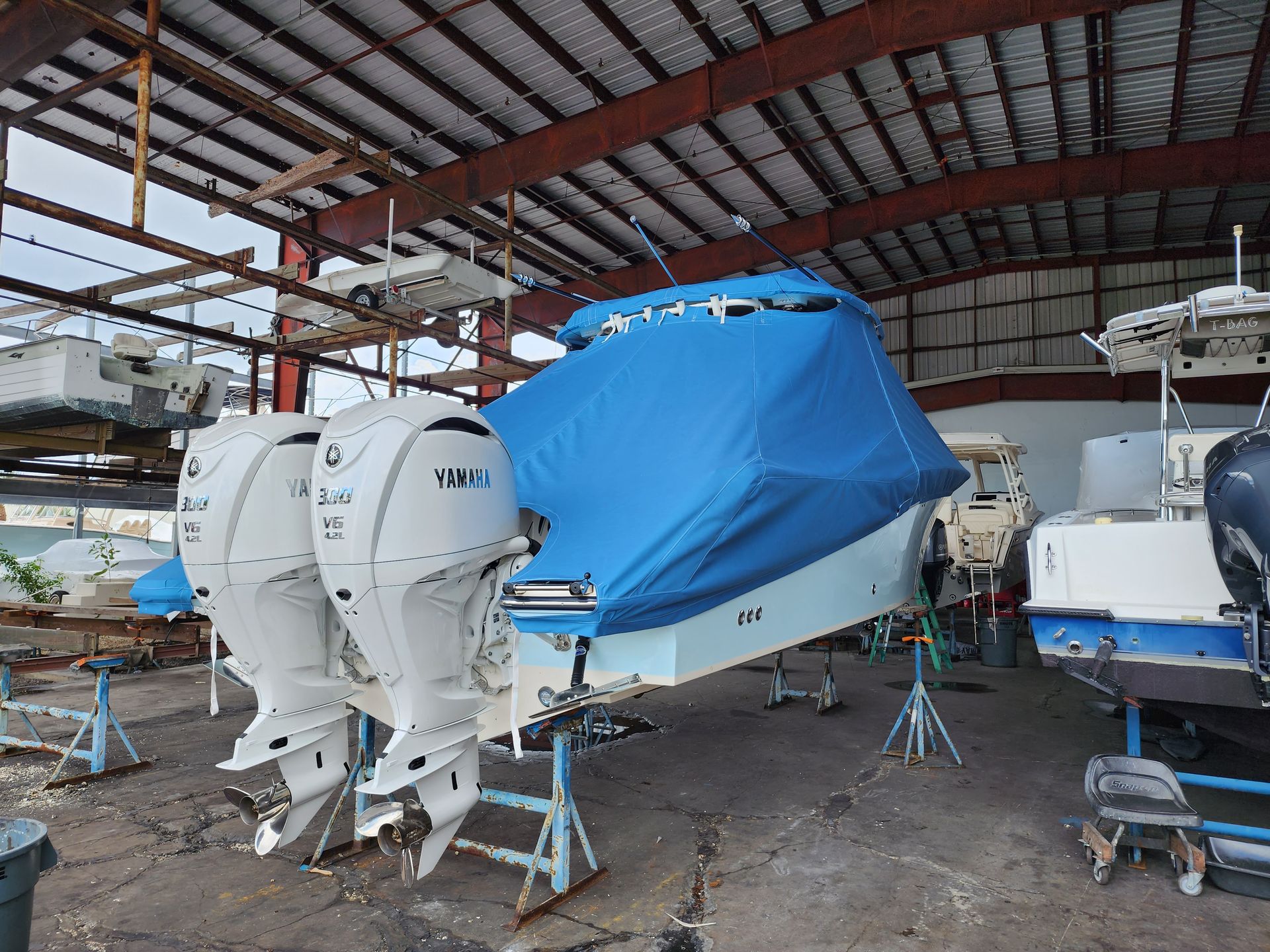 A boat with a blue cover on it is sitting in a warehouse.