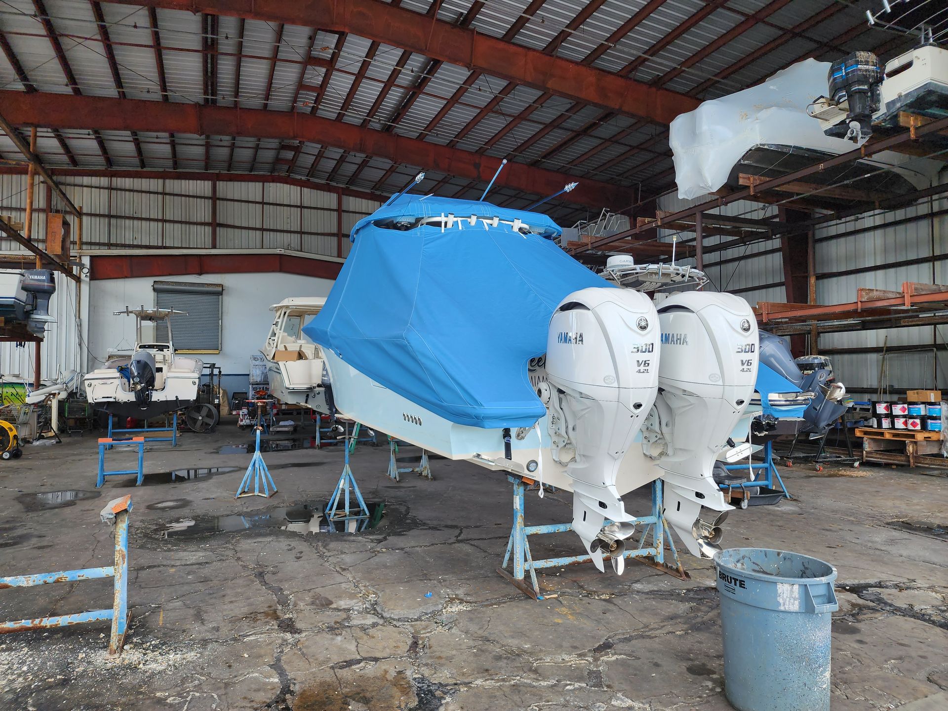 A boat is sitting in a warehouse with a blue cover on it.