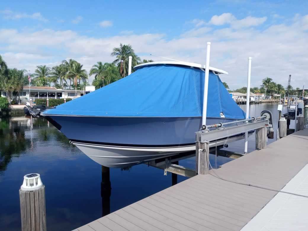A boat is docked at a dock with a blue cover on it.