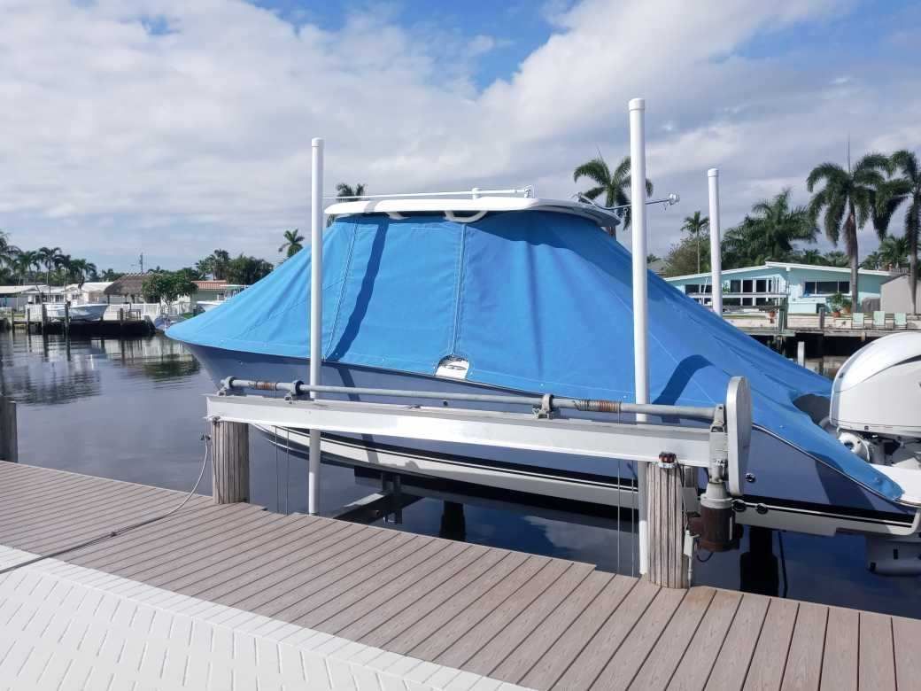 A boat is docked at a dock with a blue cover on it