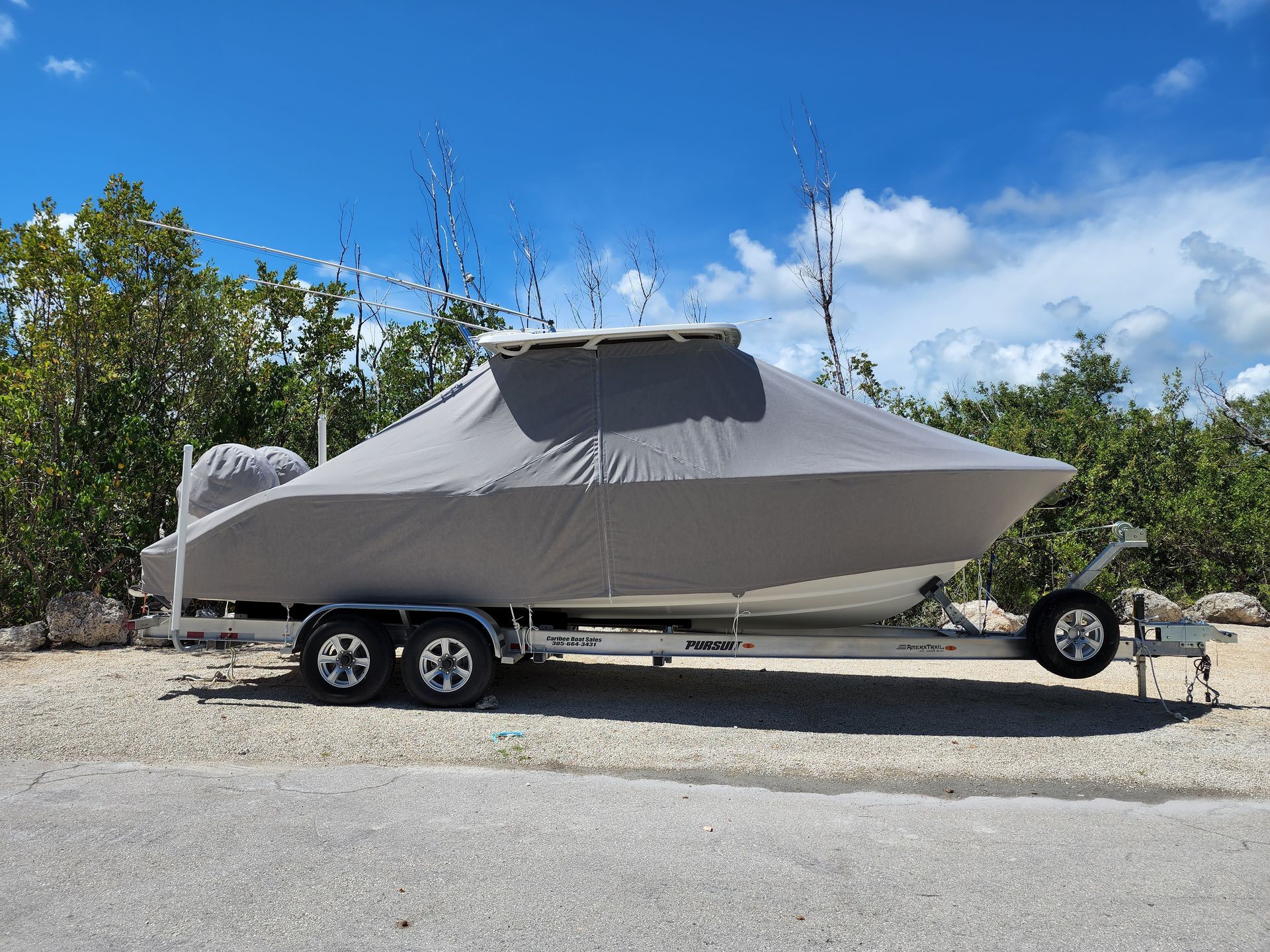 A boat with a cover on it is parked on a trailer.