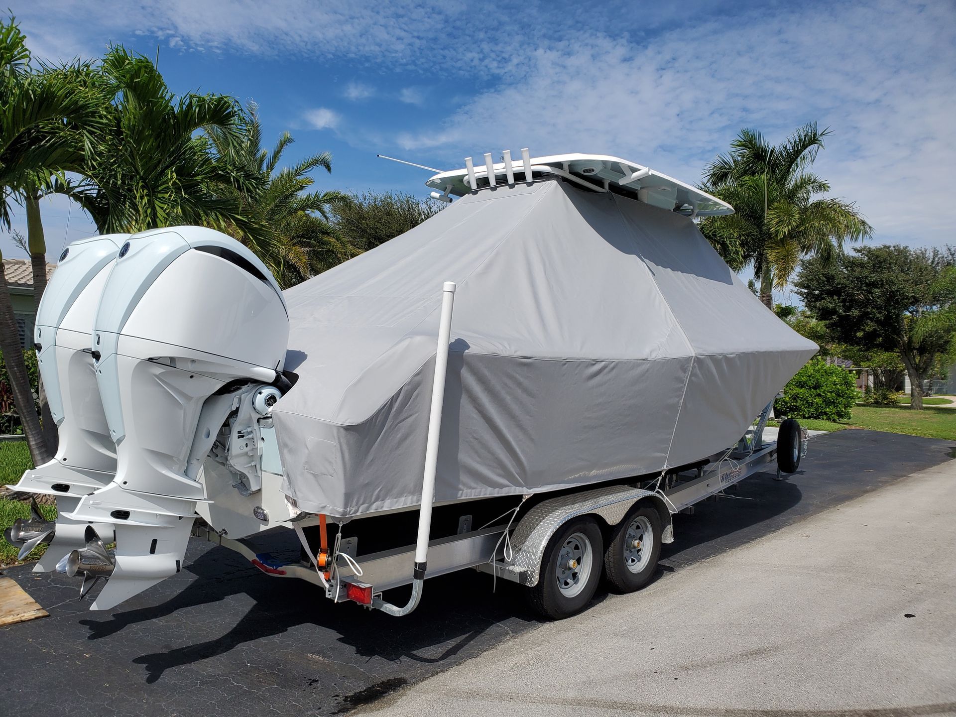 A boat with a cover on it is parked on the side of the road.