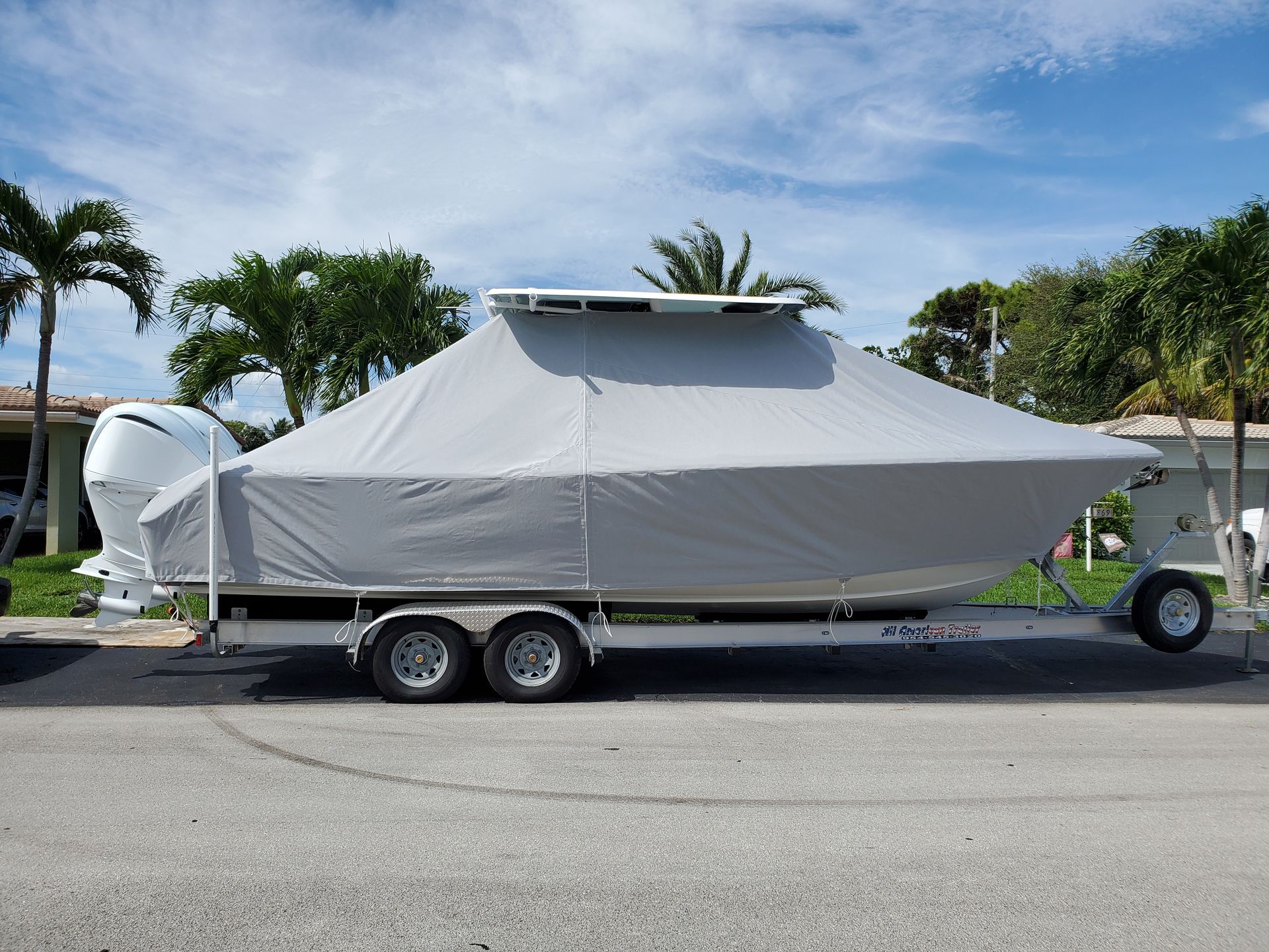 A boat with a cover on it is parked on the side of the road.