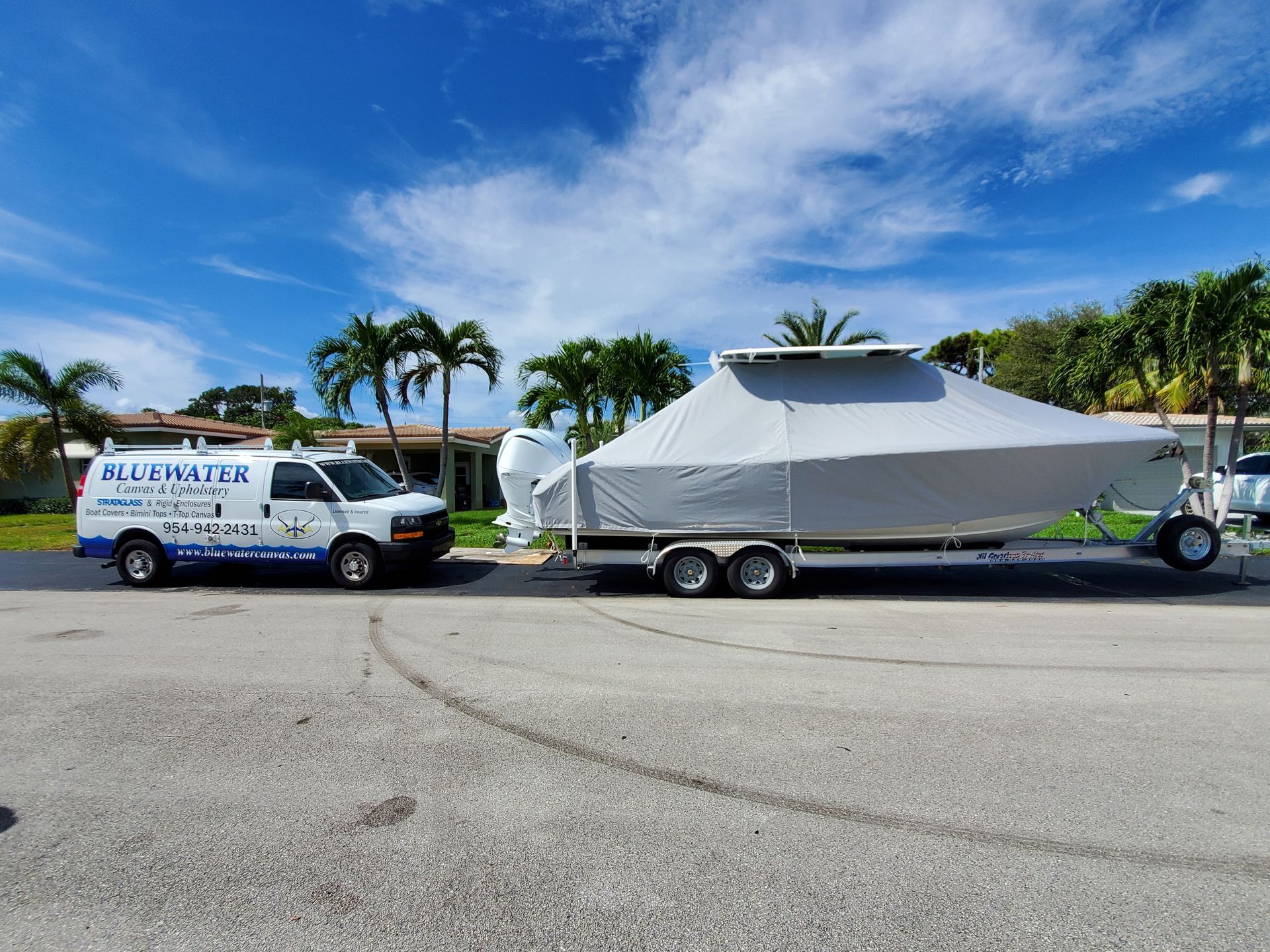 A white van is towing a boat on a trailer.