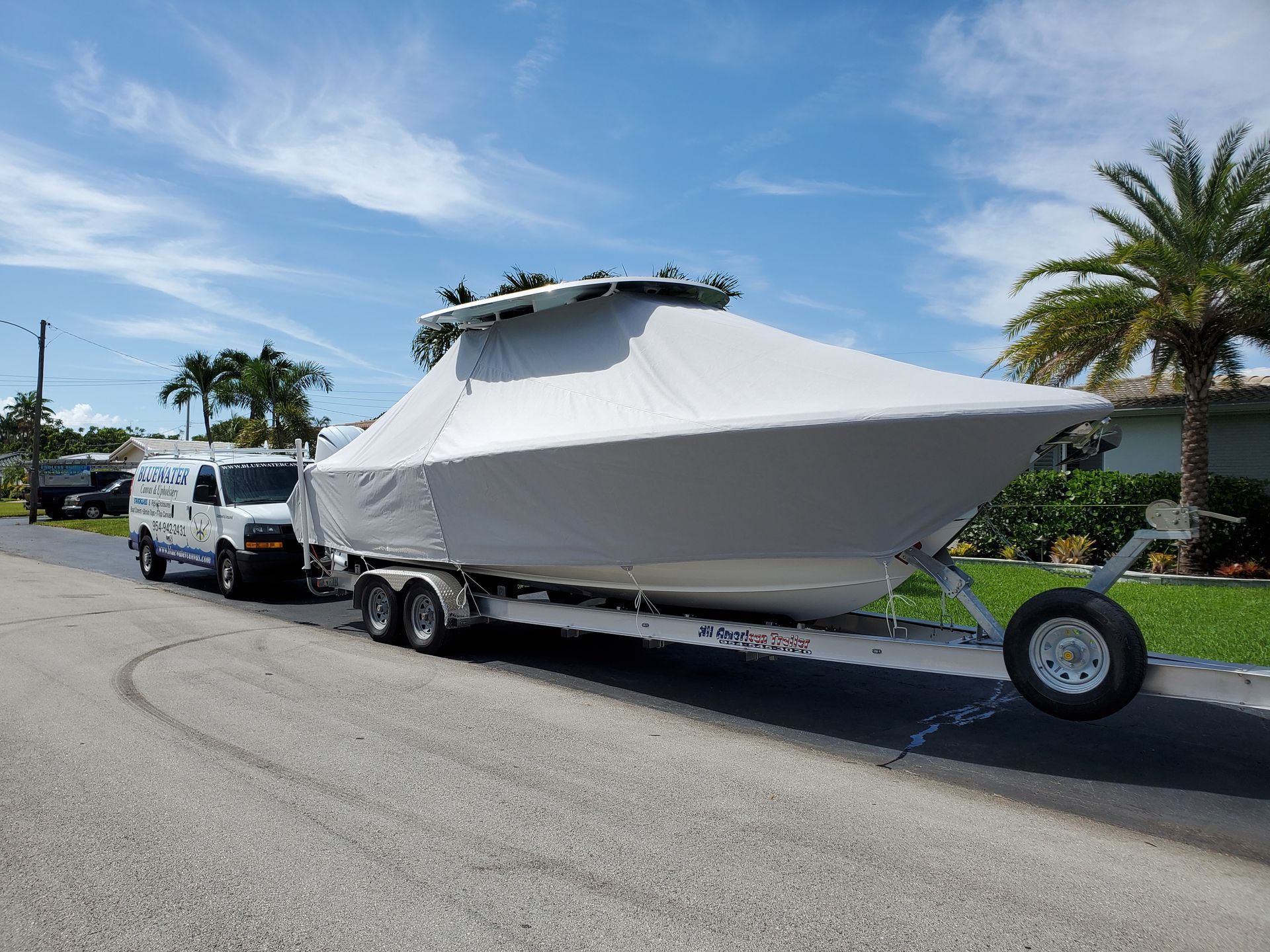 A boat is covered in a white tarp on a trailer.
