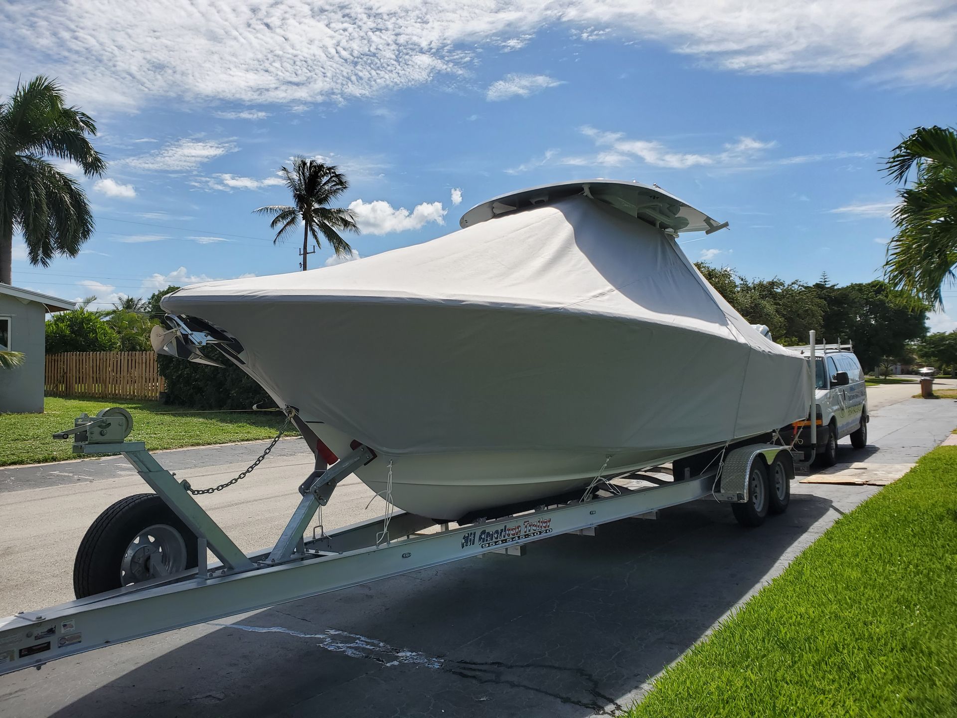 A boat on a trailer is parked on the side of the road