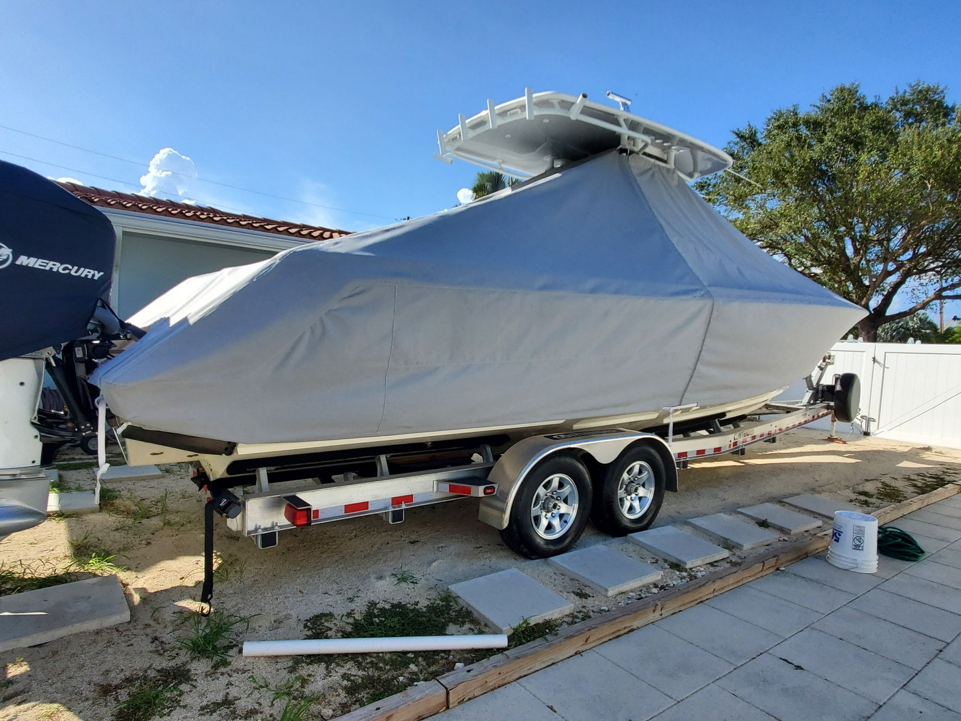 A boat with a cover on it is parked on a trailer.