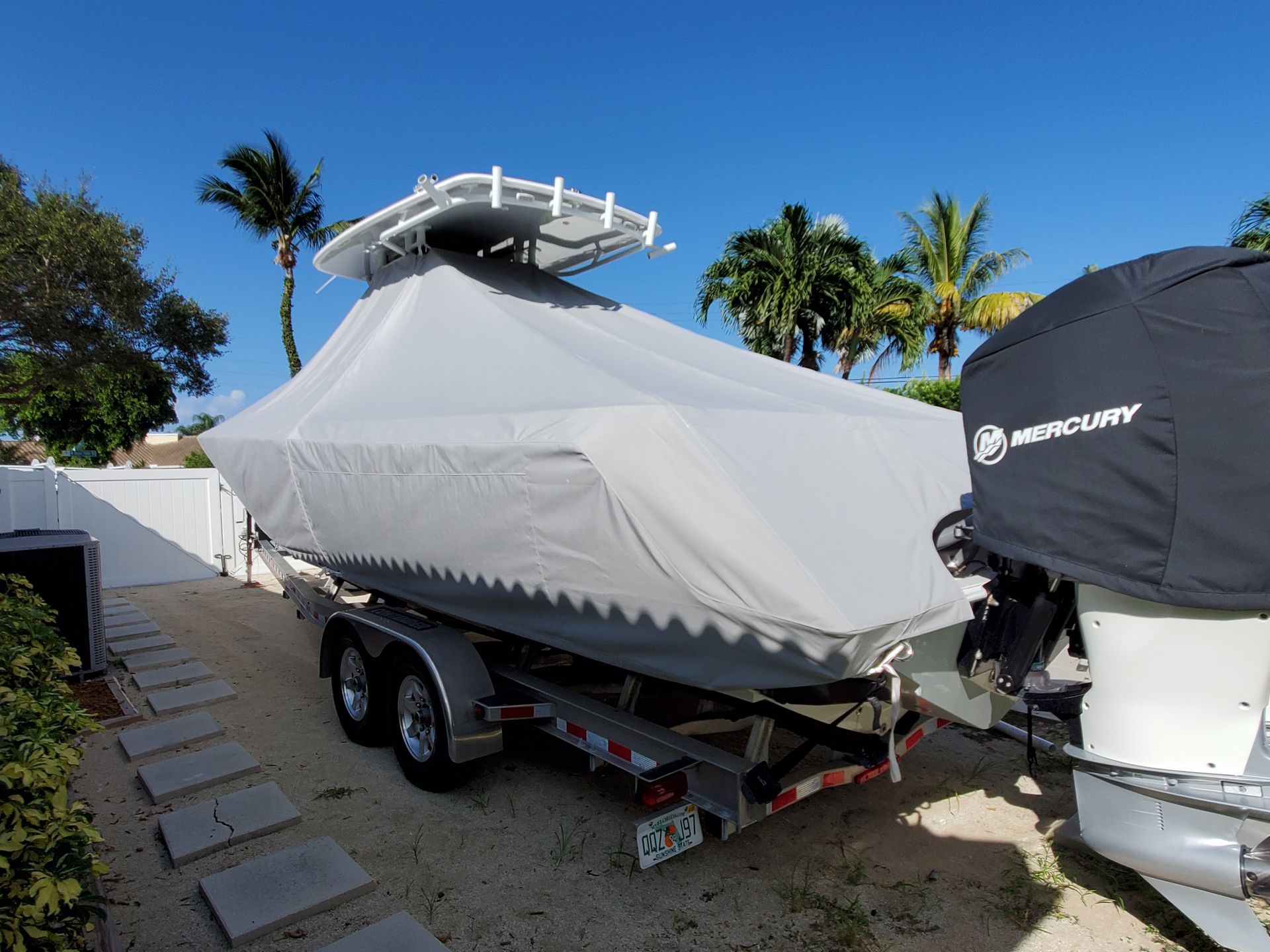 A boat with a cover on it is parked on a trailer.