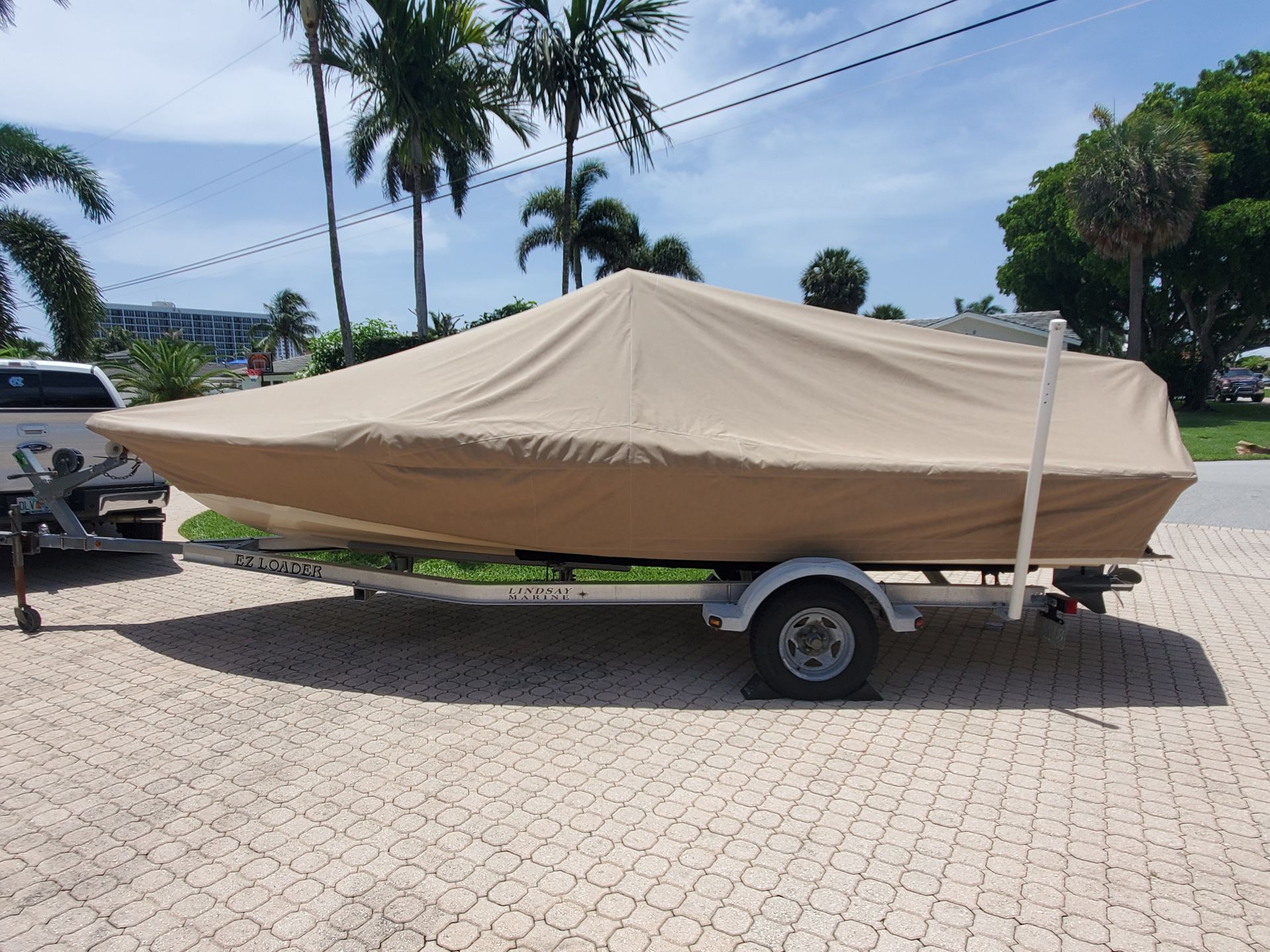A boat with a cover on it is parked on a trailer.