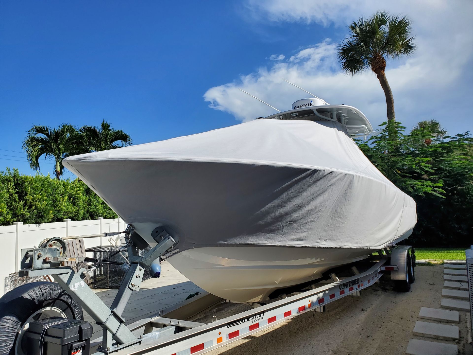 A boat is sitting on a trailer with a white cover on it.
