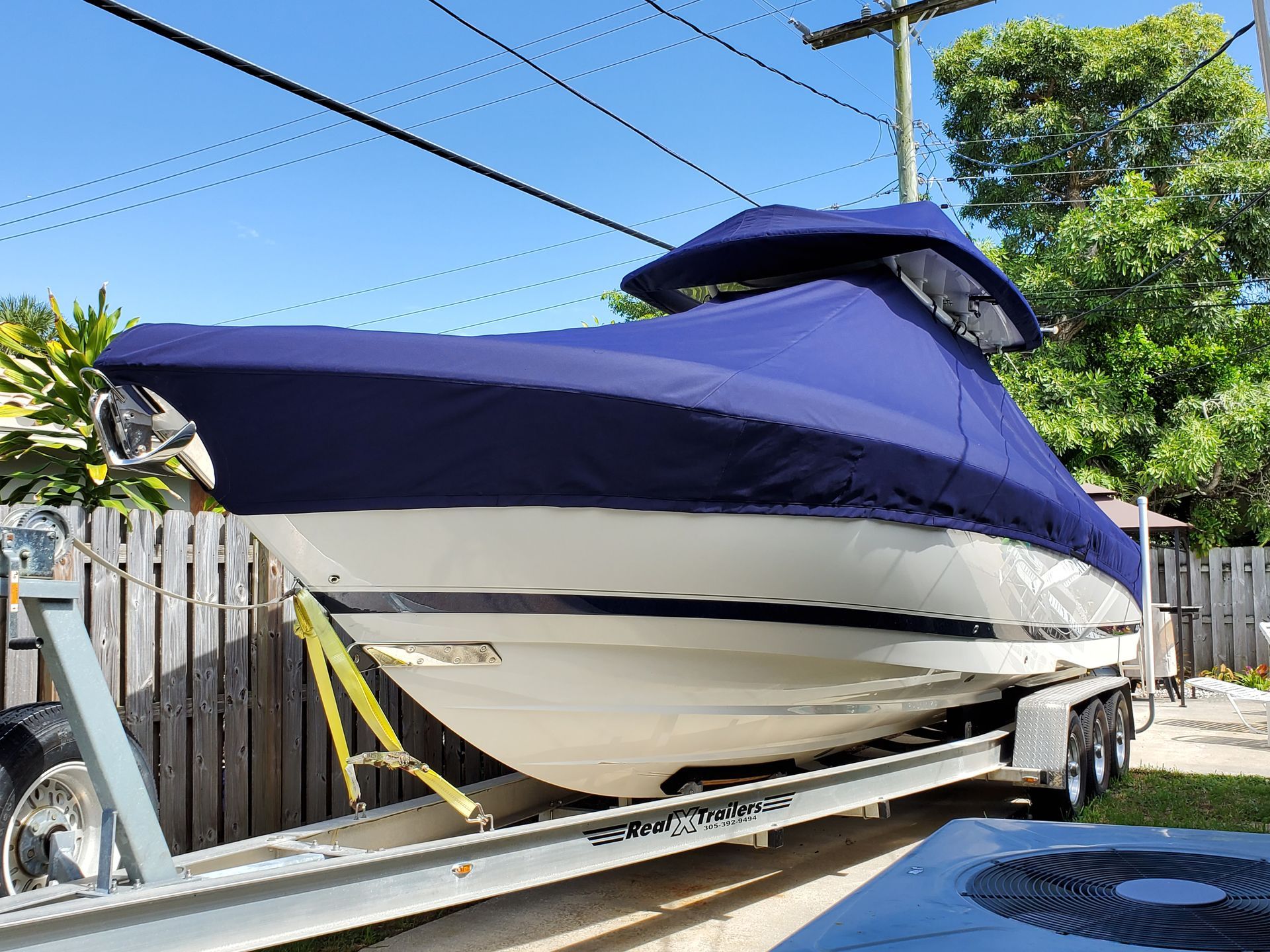 A boat is sitting on a trailer with a blue cover on it.