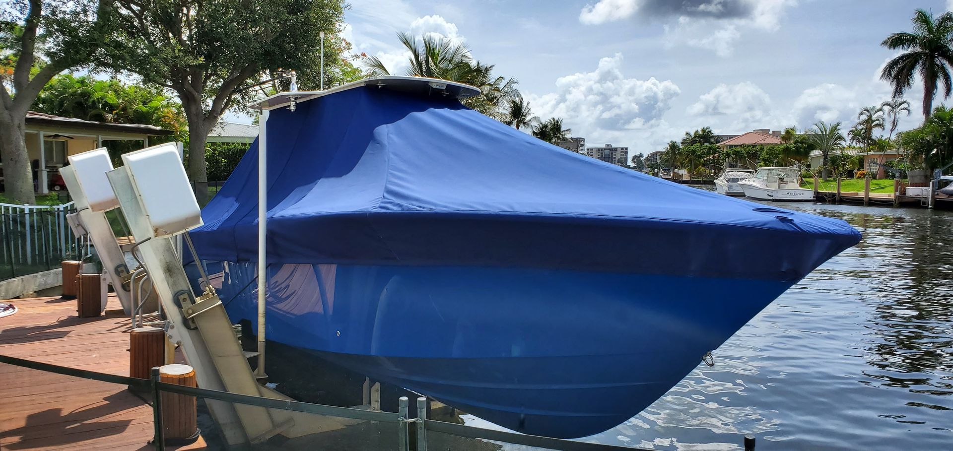A blue boat is sitting on a lift in the water.
