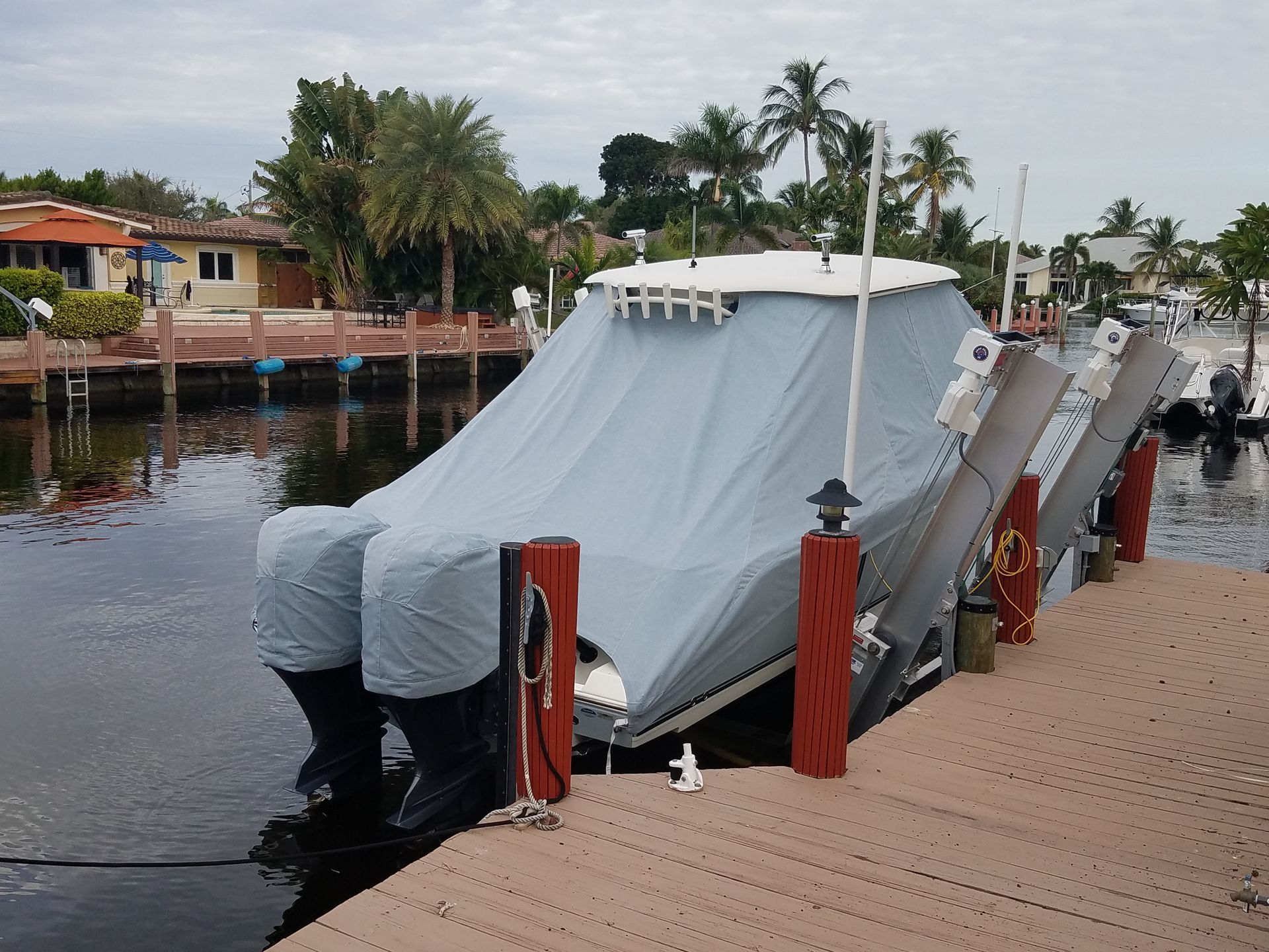 A boat covered in a blue cover is docked at a dock