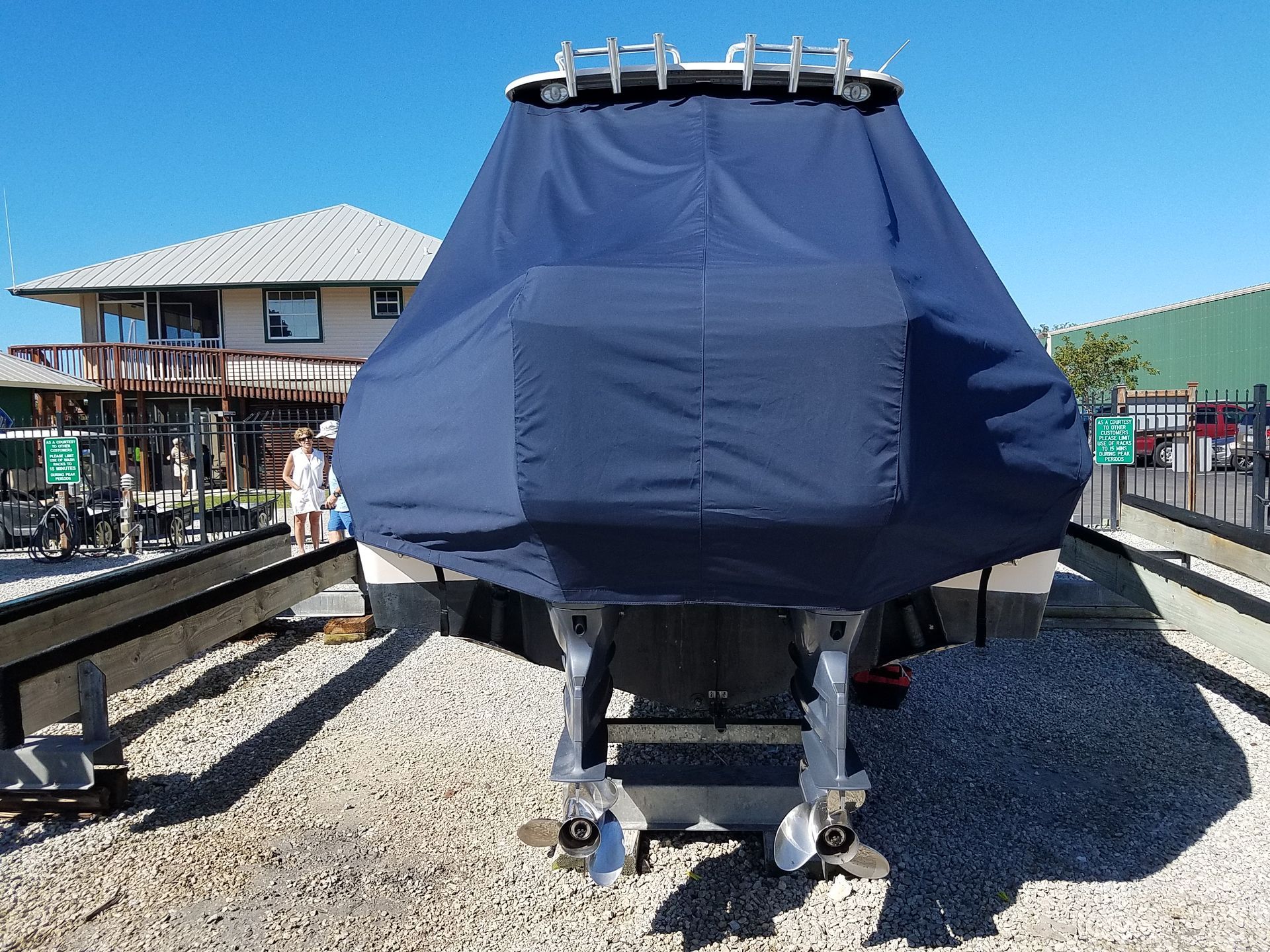 A boat with a blue cover on it is parked on gravel