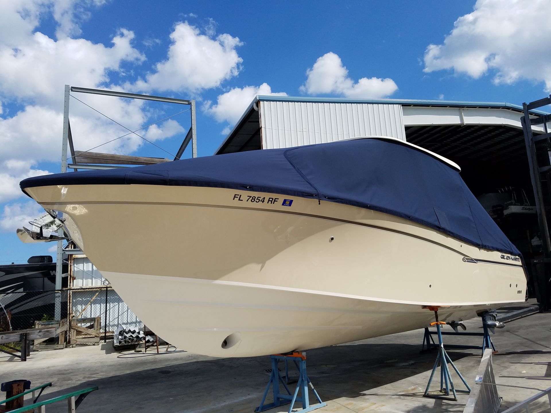 A boat with a blue cover on it is parked in front of a building.