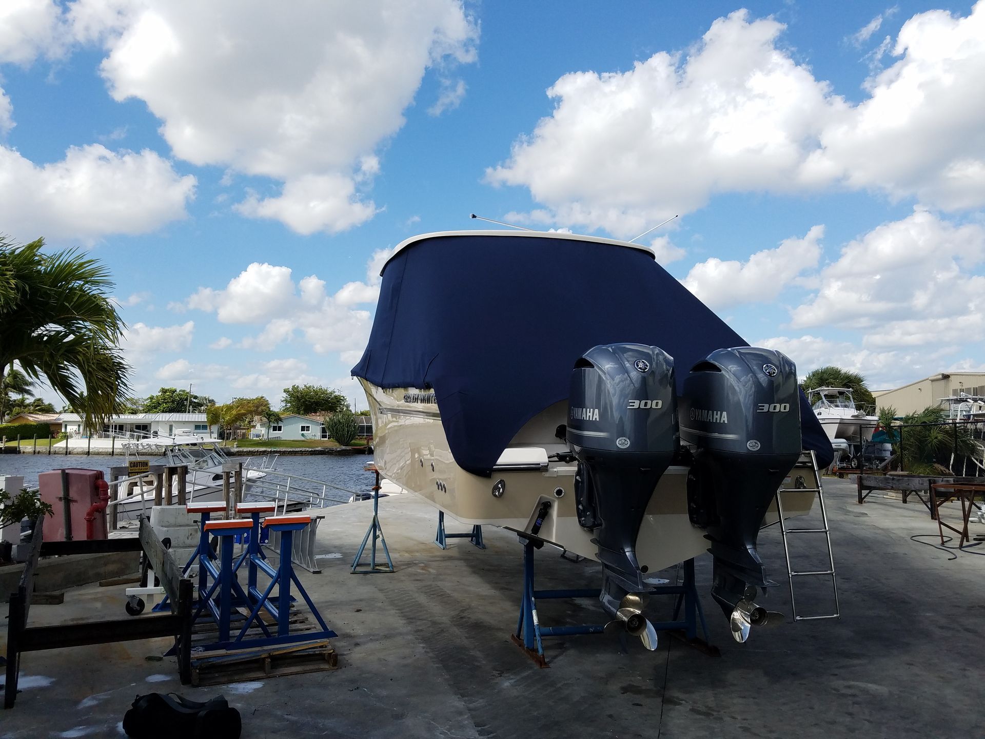 A boat with two outboard motors is covered in a blue tarp.