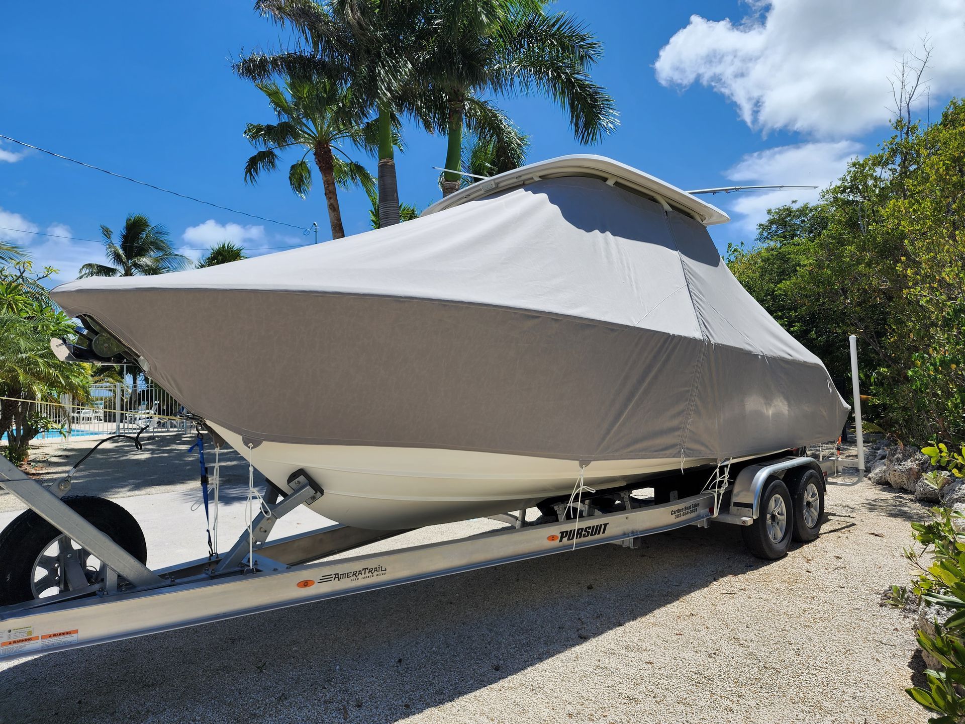 A boat with a cover on it is parked on a trailer.