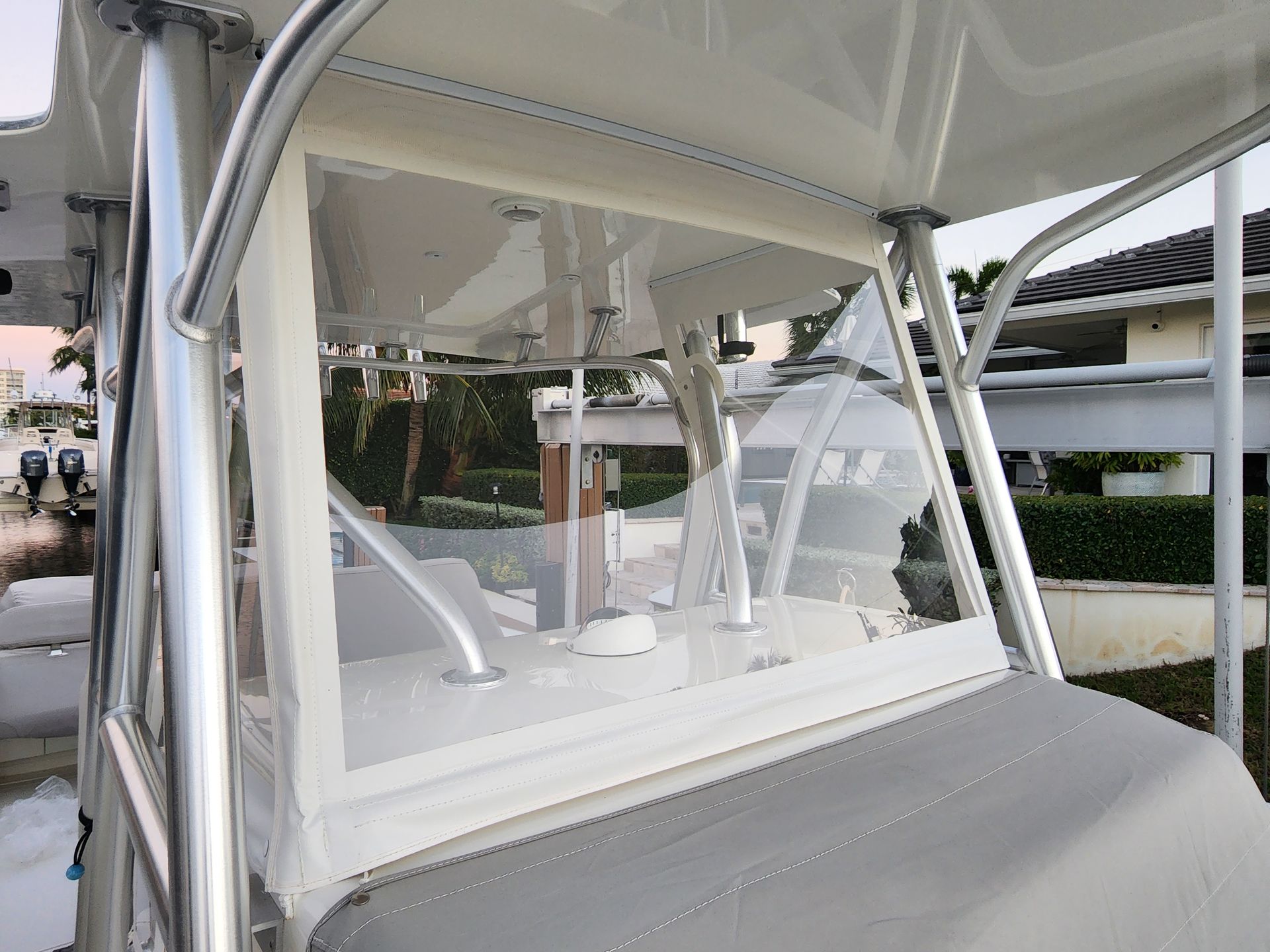 A white boat with a clear windshield is parked in front of a house.