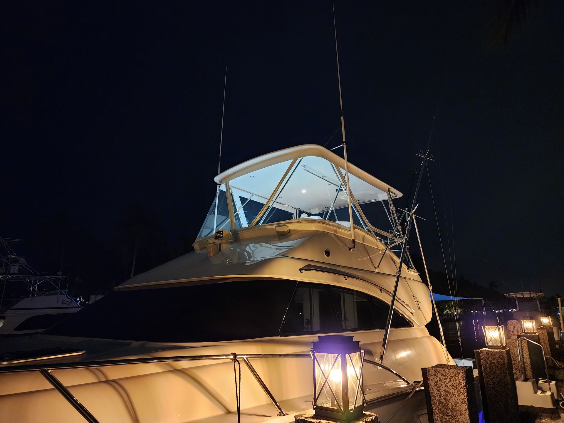 A boat is docked in a marina at night.