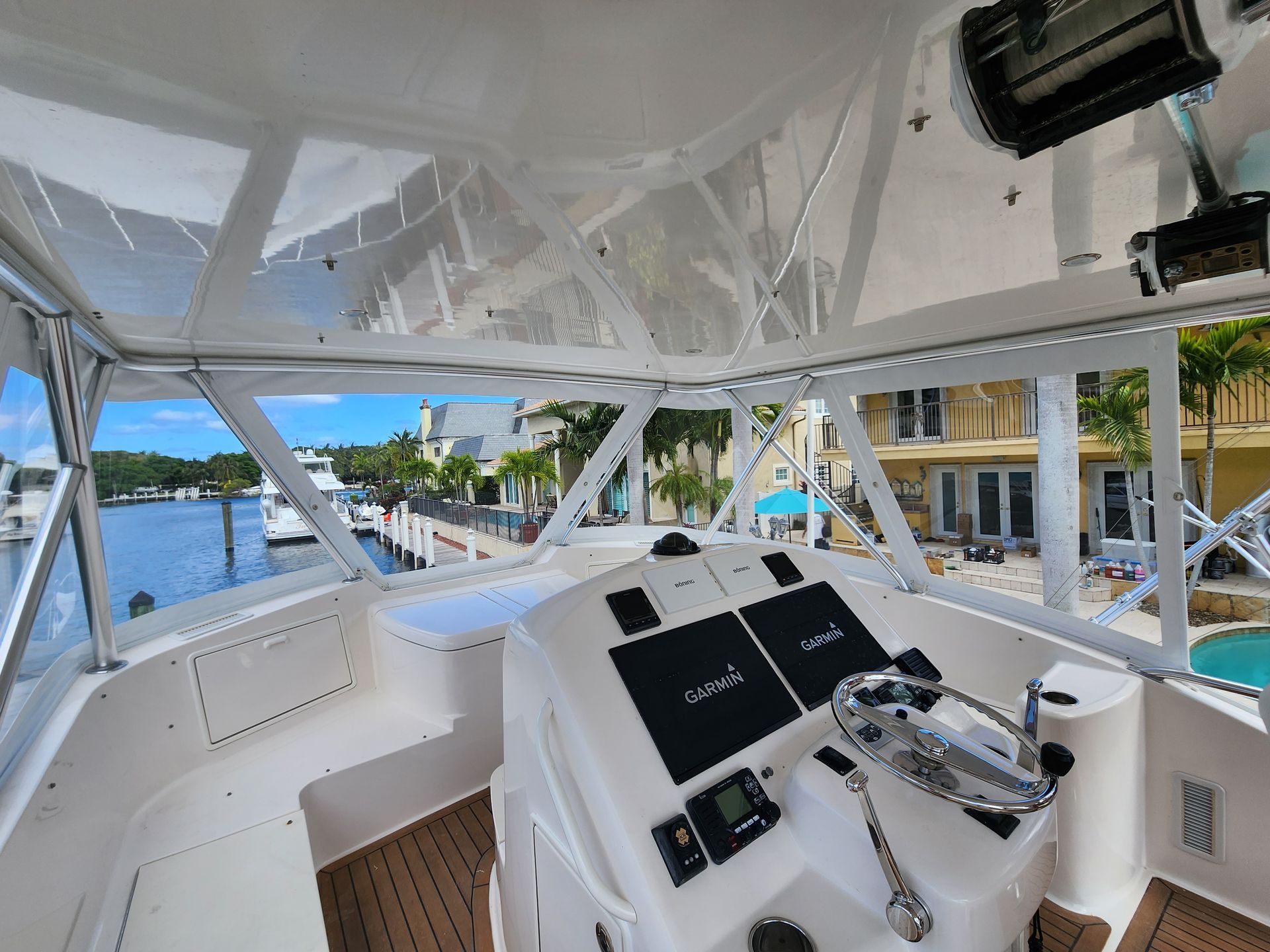 The inside of a boat with a steering wheel and a view of the water.
