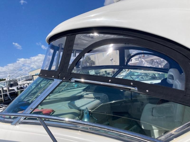 A white boat with a clear windshield is parked in a marina.