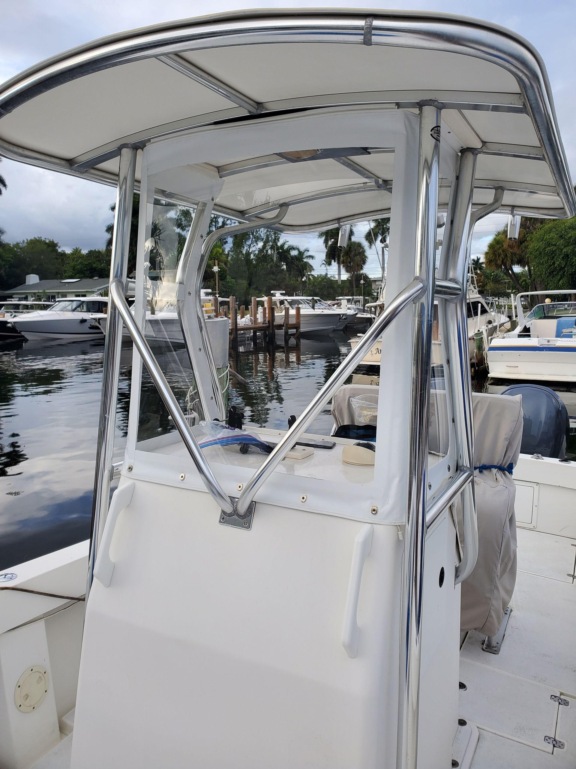 A white boat with a canopy is docked in the water.