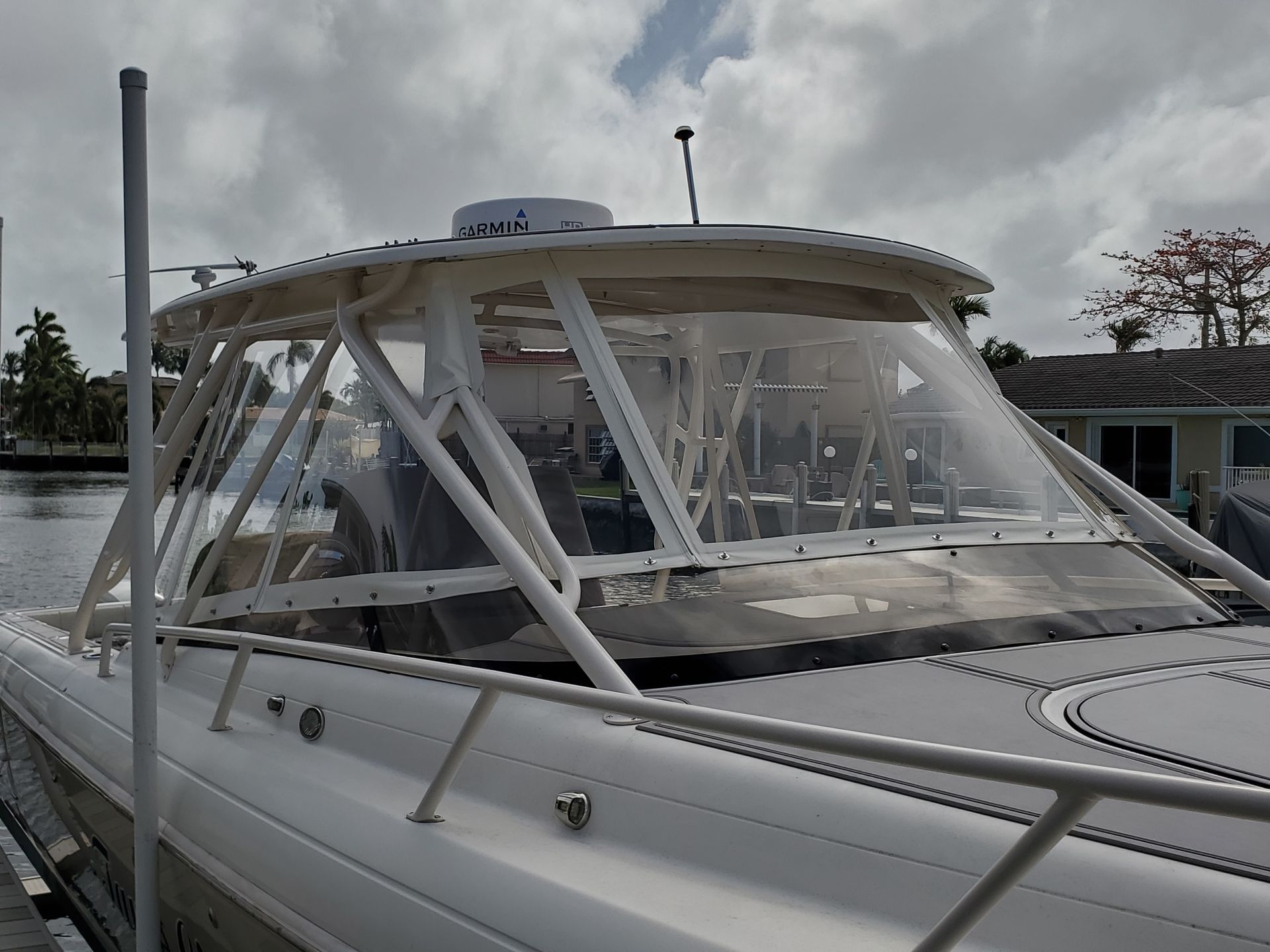 A white boat with a clear windshield is docked at a dock