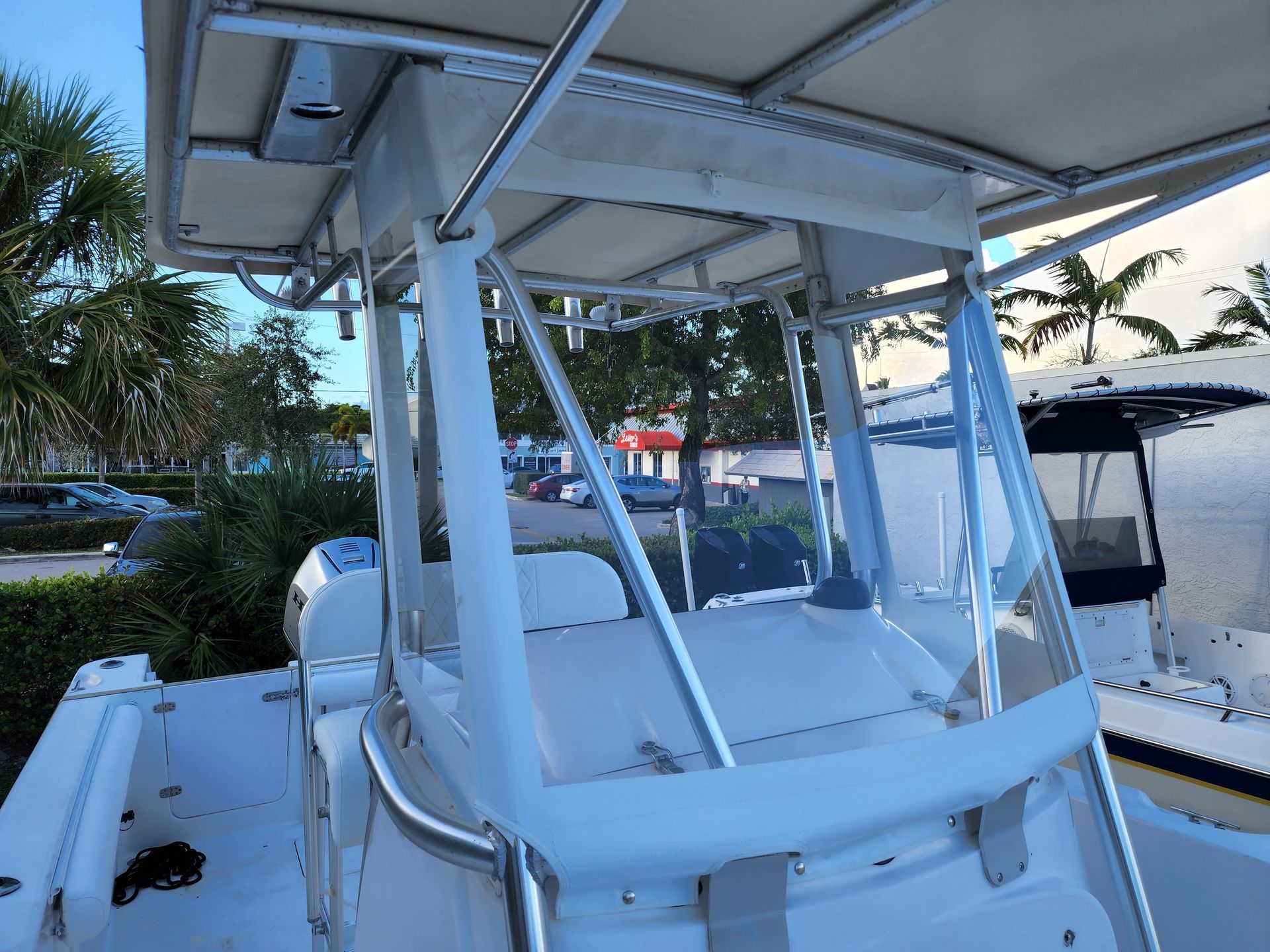 A white boat with a clear windshield is parked in a marina.