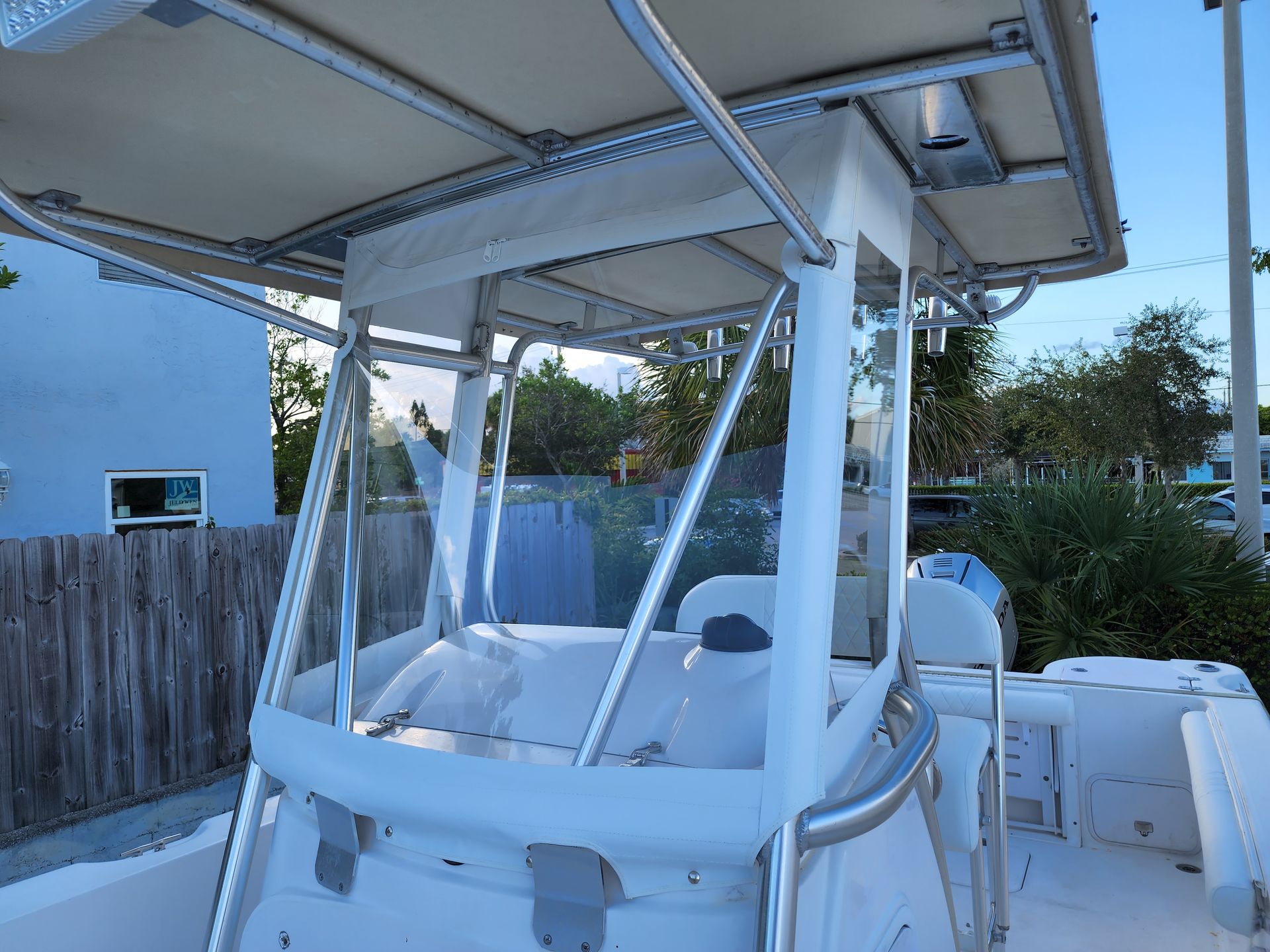 A white boat with a canopy on top of it is parked in front of a building.
