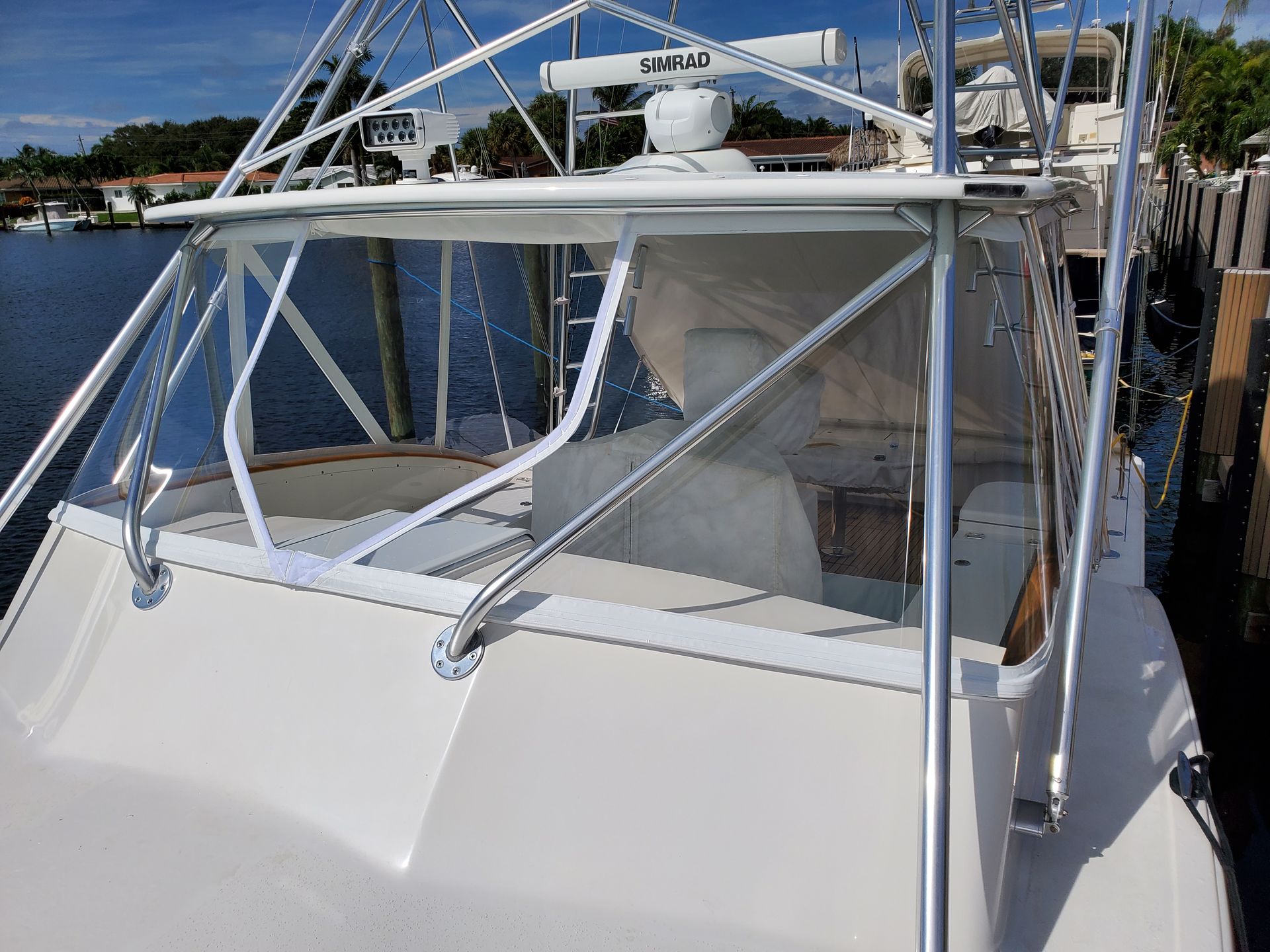 A white boat is docked at a dock in the water.