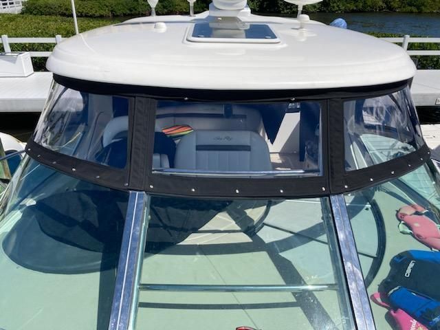 A boat with a clear windshield is docked at a dock