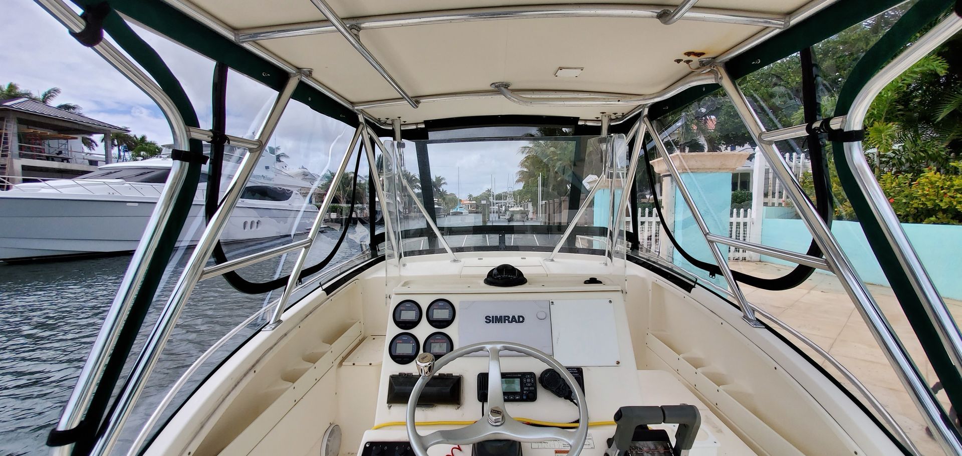 The front of a boat with a steering wheel and a canopy.
