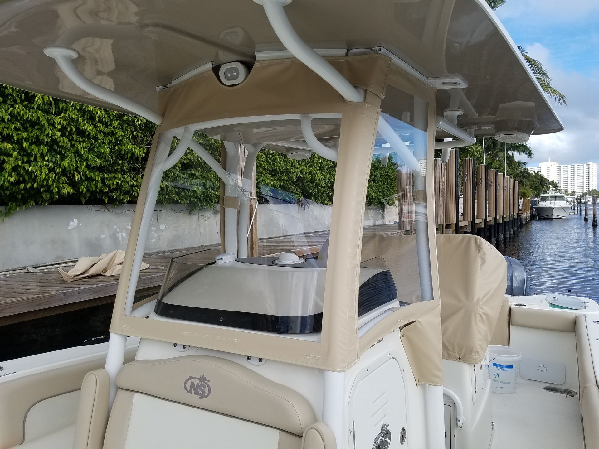 A white boat with a tan cover on it is docked at a dock.