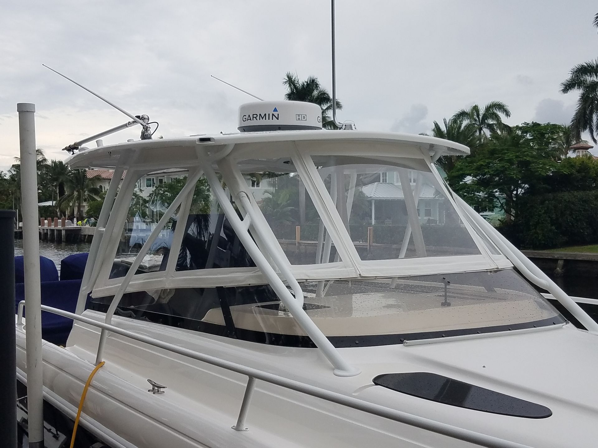 A white boat with a large windshield is docked at a dock.
