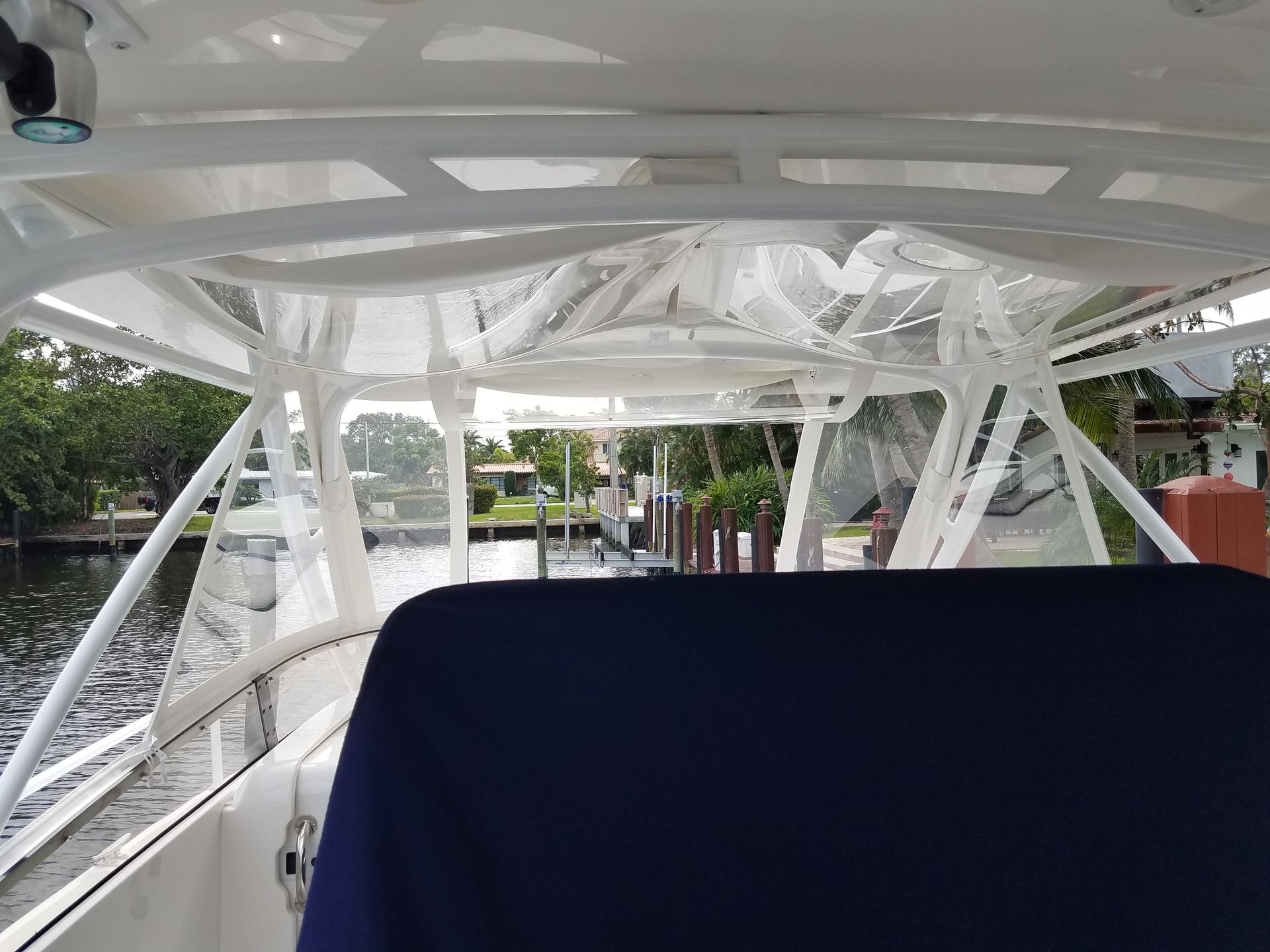 The inside of a boat with a blue seat and a white roof.