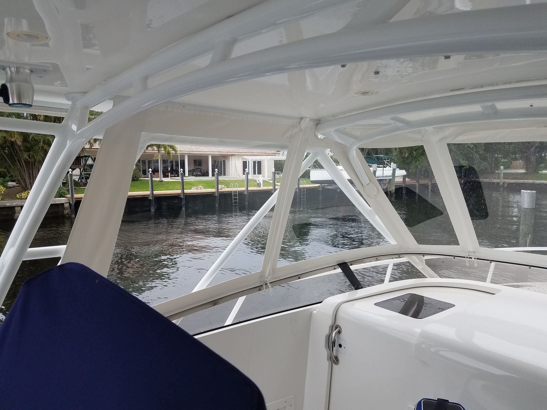 The inside of a boat with a view of the water and a house in the background.