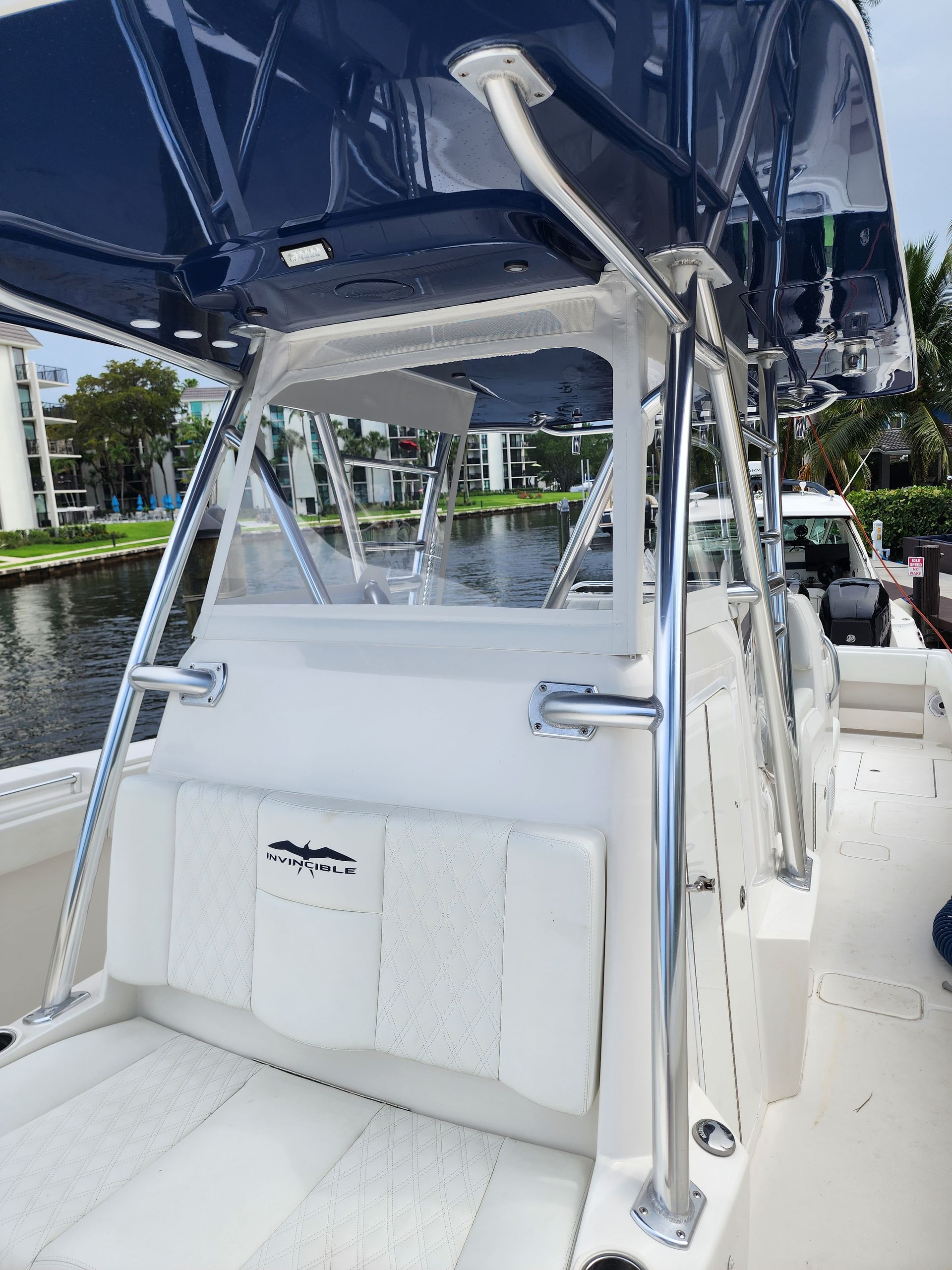 A white boat with a blue canopy is sitting on a body of water.