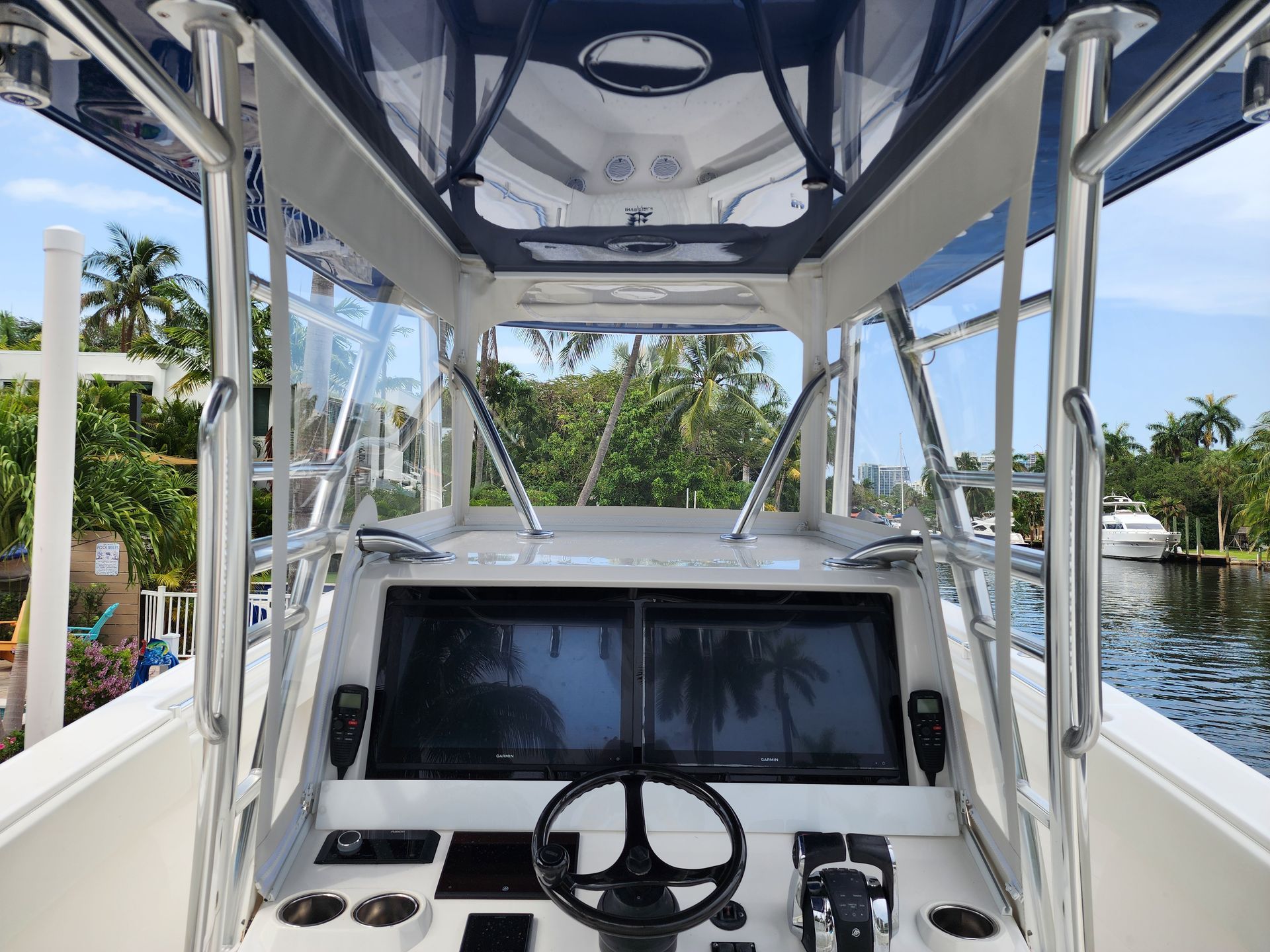 The inside of a boat with a steering wheel and a large screen.
