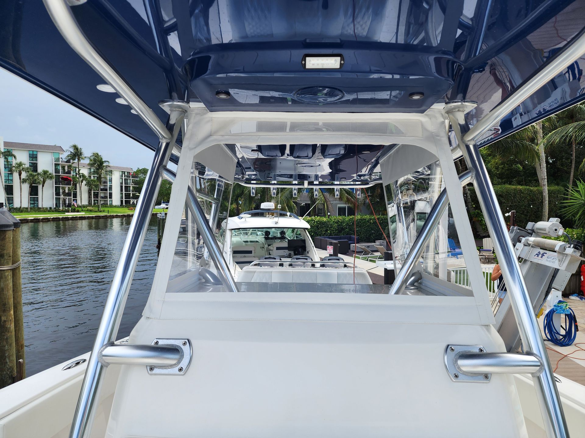 The back of a boat with a blue canopy is sitting in the water.