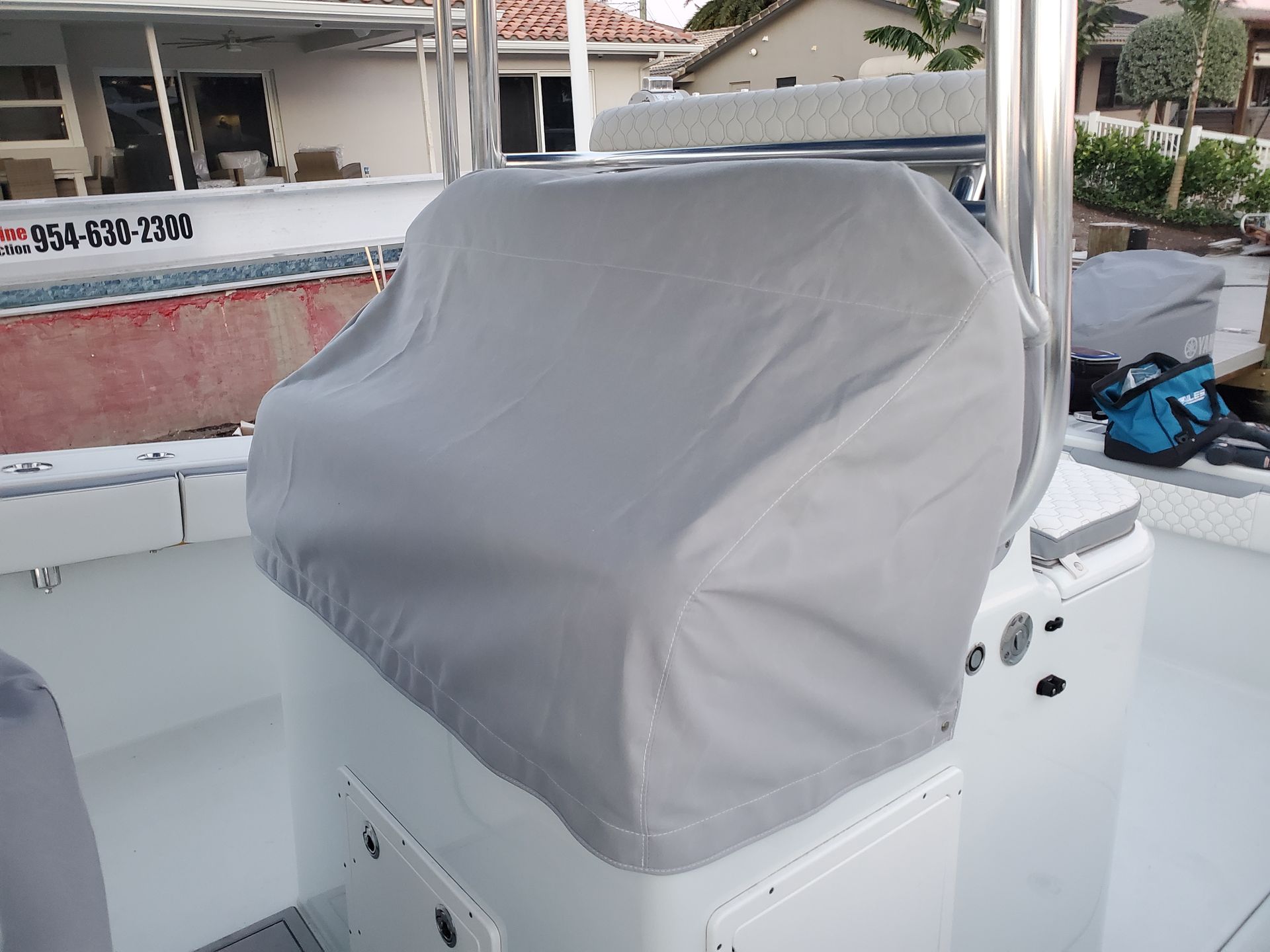 A white boat with a grey cover on the steering wheel