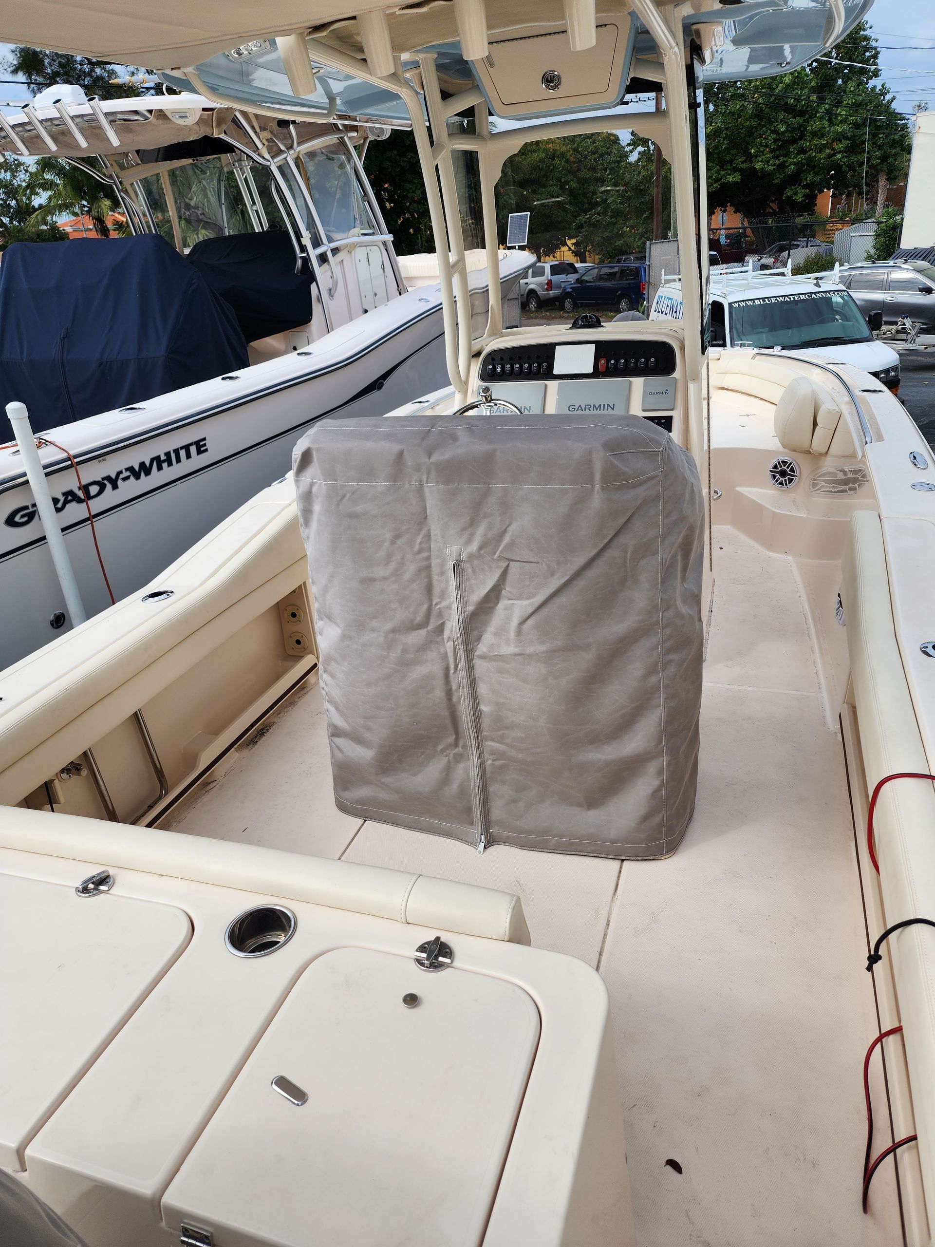A boat with a cover on the cockpit is parked next to another boat.